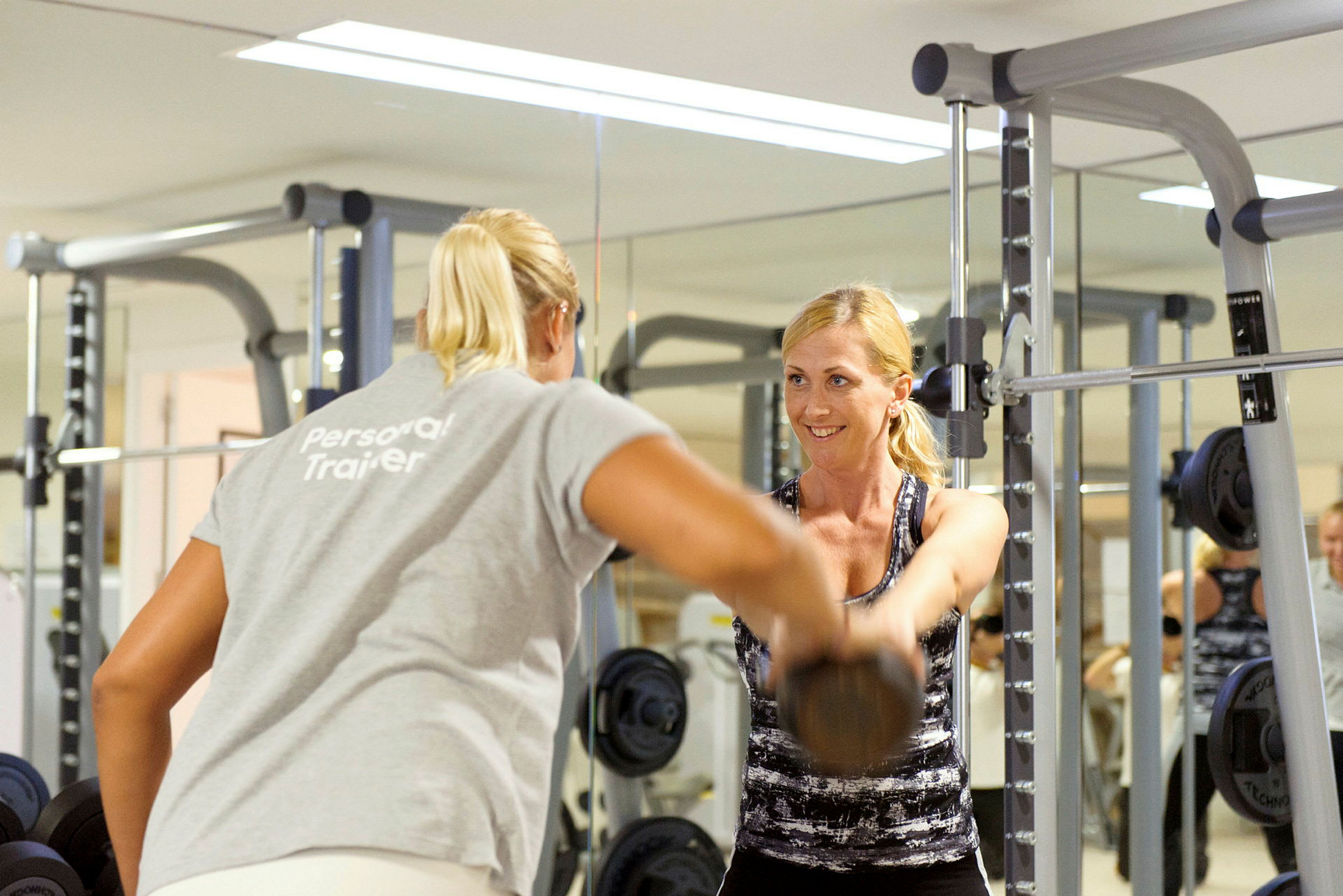 Personlig tränare hjälper en kvinna att träna med hantlar i ett gym. (AI-genererad text)