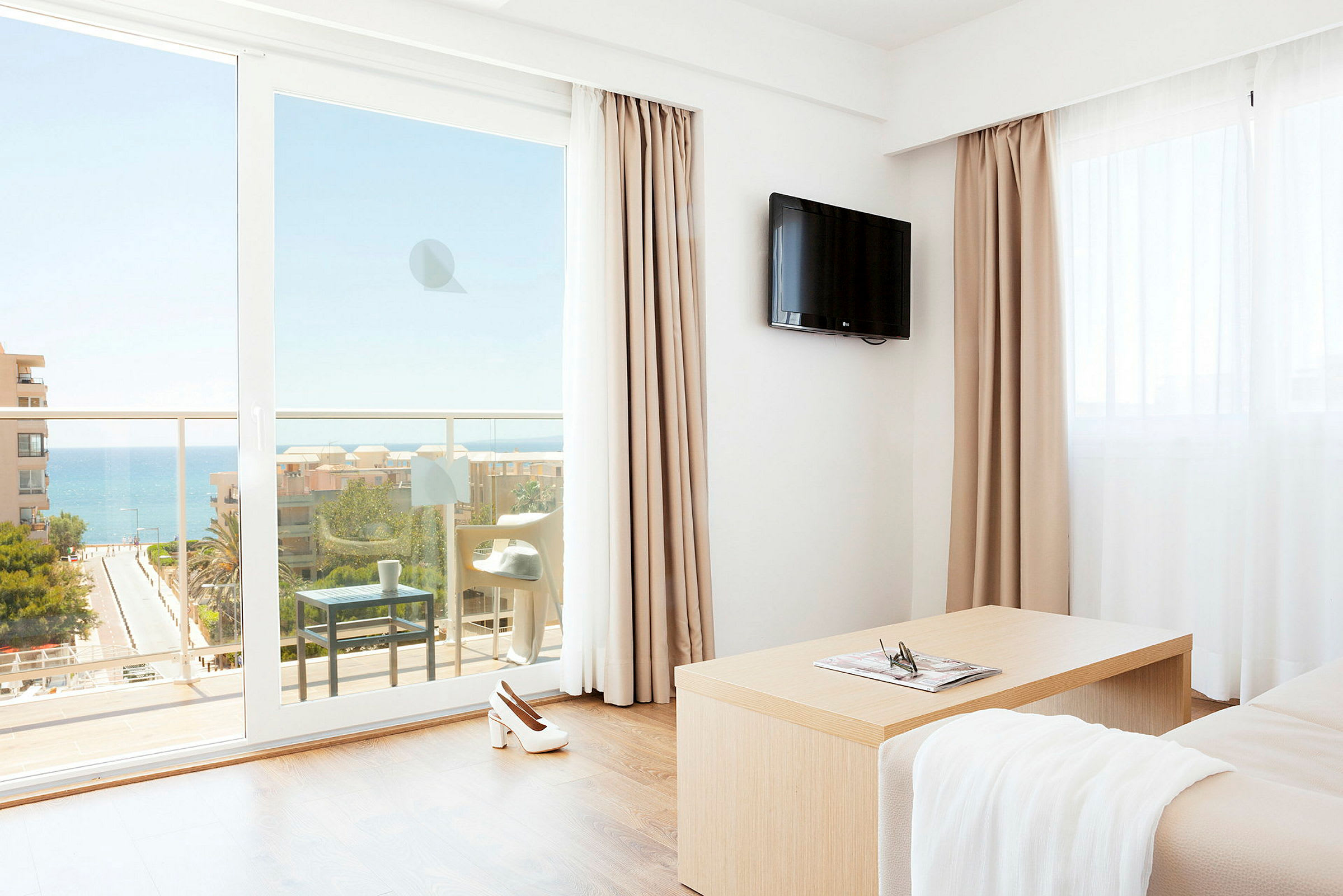 Ett hotellrum med utsikt över havet genom en balkong. (AI-genererad text)