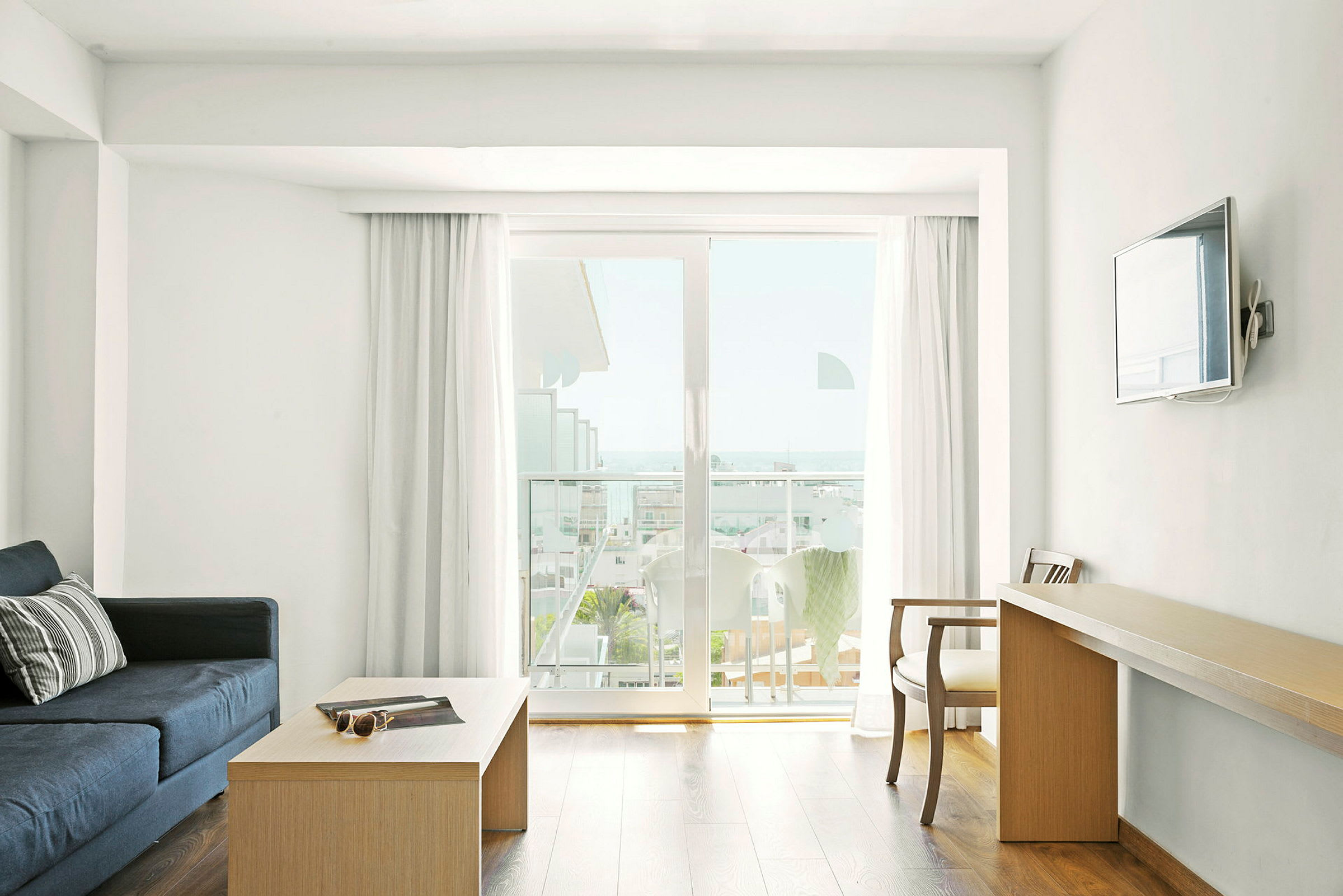 Ett hotellrum med soffbord, soffa, skrivbord och balkong med utsikt. (AI-genererad text)