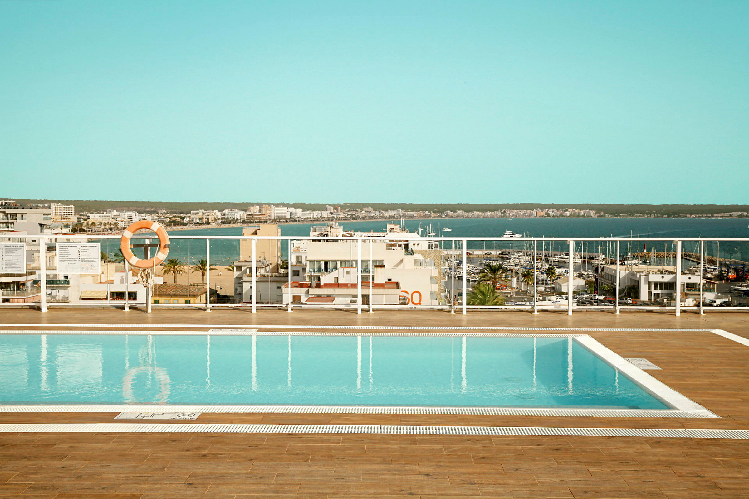 Poolområde med utsikt över marinor och hav. (AI-genererad text)