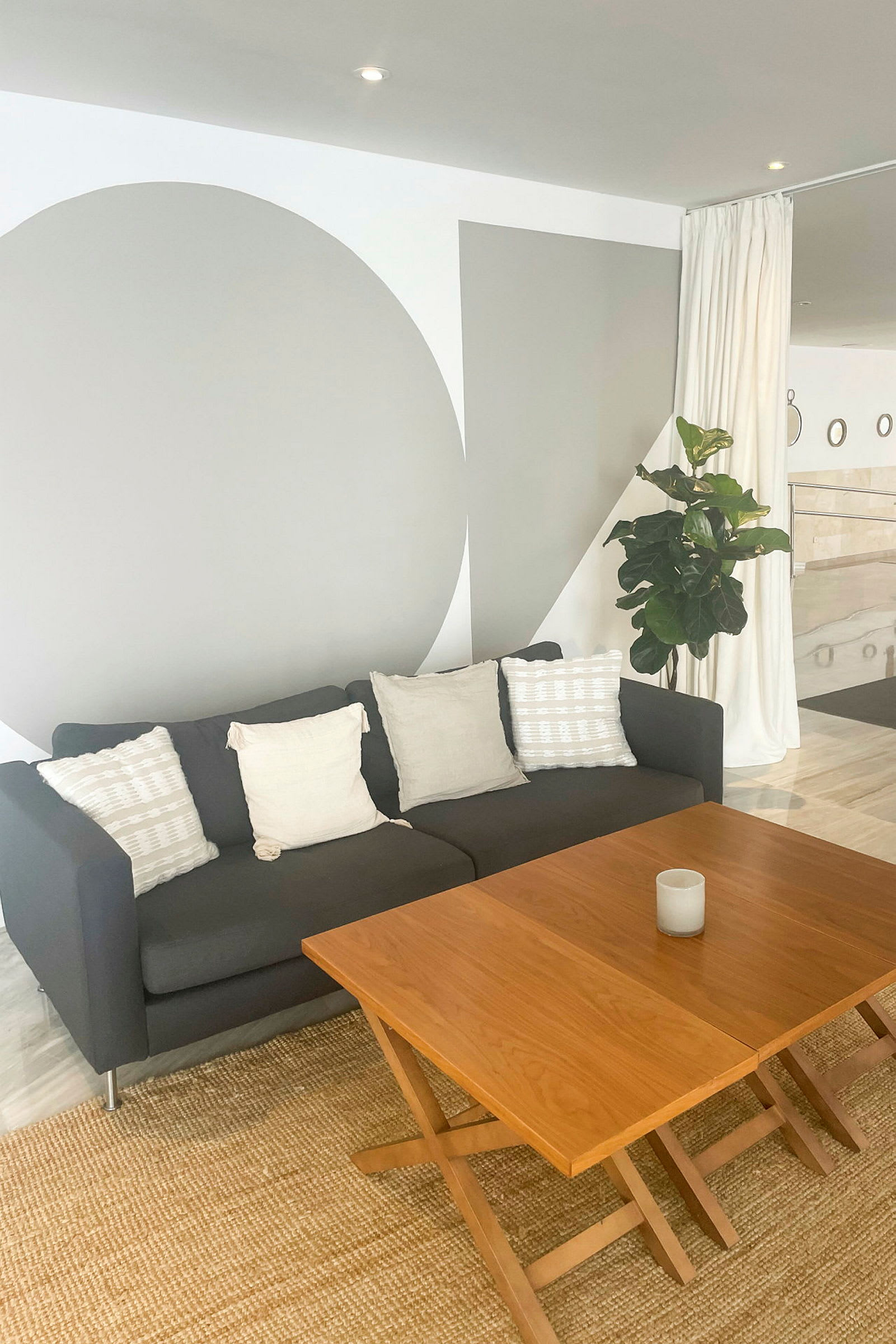 En grå soffa med vita kuddar framför ett träbord. (AI-genererad text)