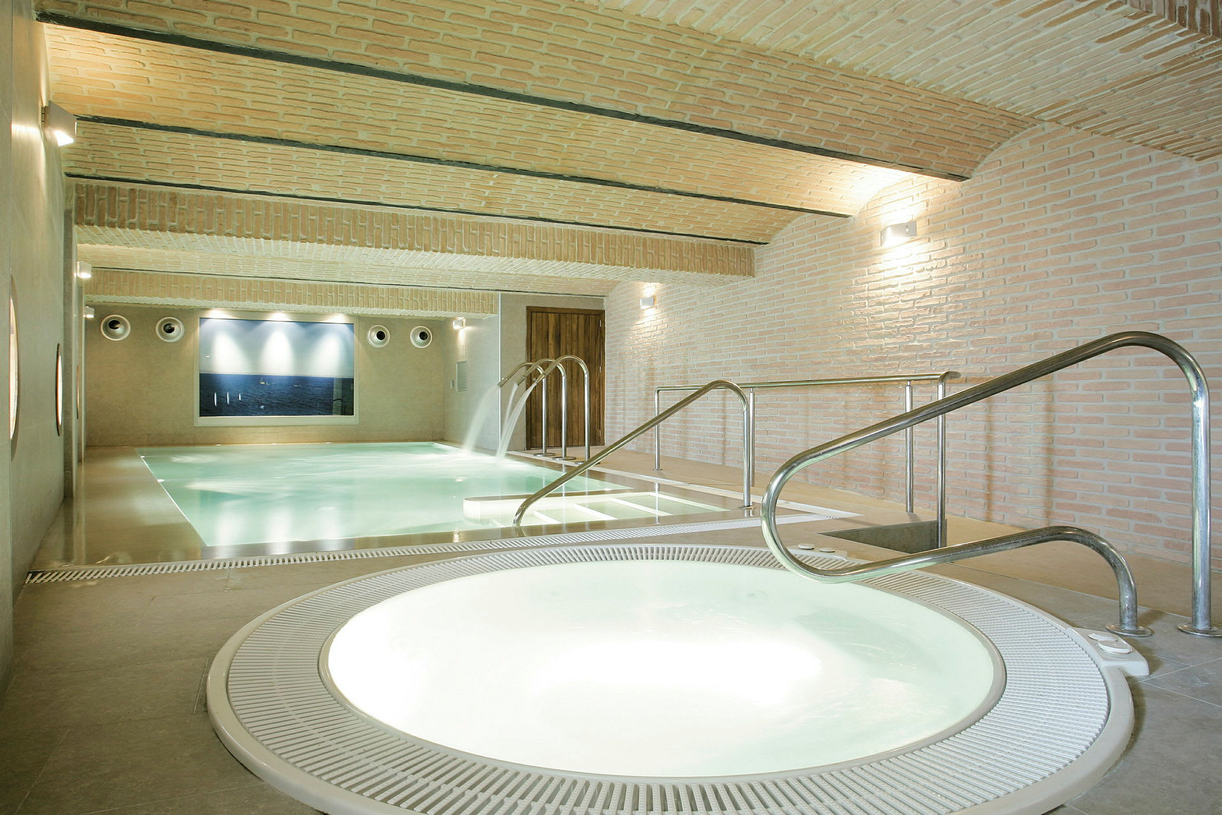 Inomhuspoolområde med jacuzzi och pool med vattenfall. (AI-genererad text)