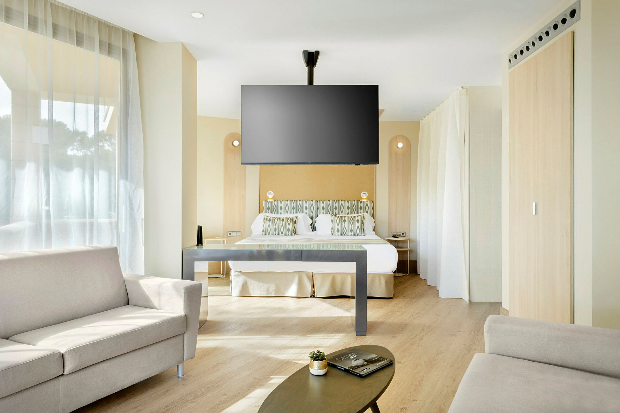Ett hotellrum med säng, soffa och väggmonterad TV. (AI-genererad text)