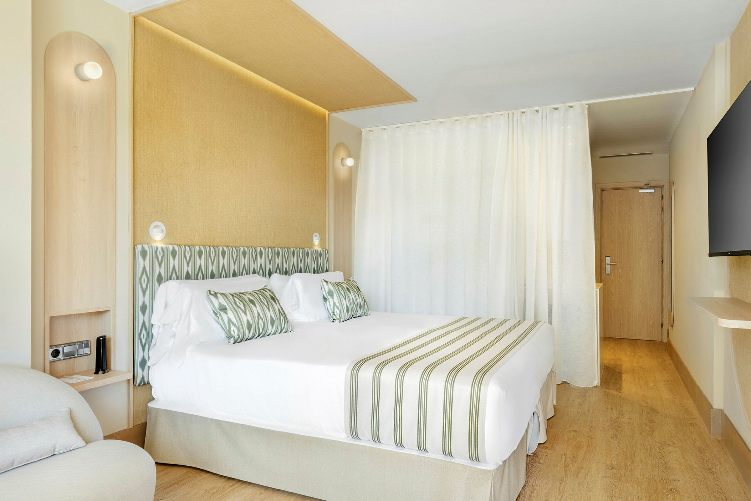 Hotellrum med dubbelsäng, grön-vit randig inredning och ljusa möbler. (AI-genererad text)