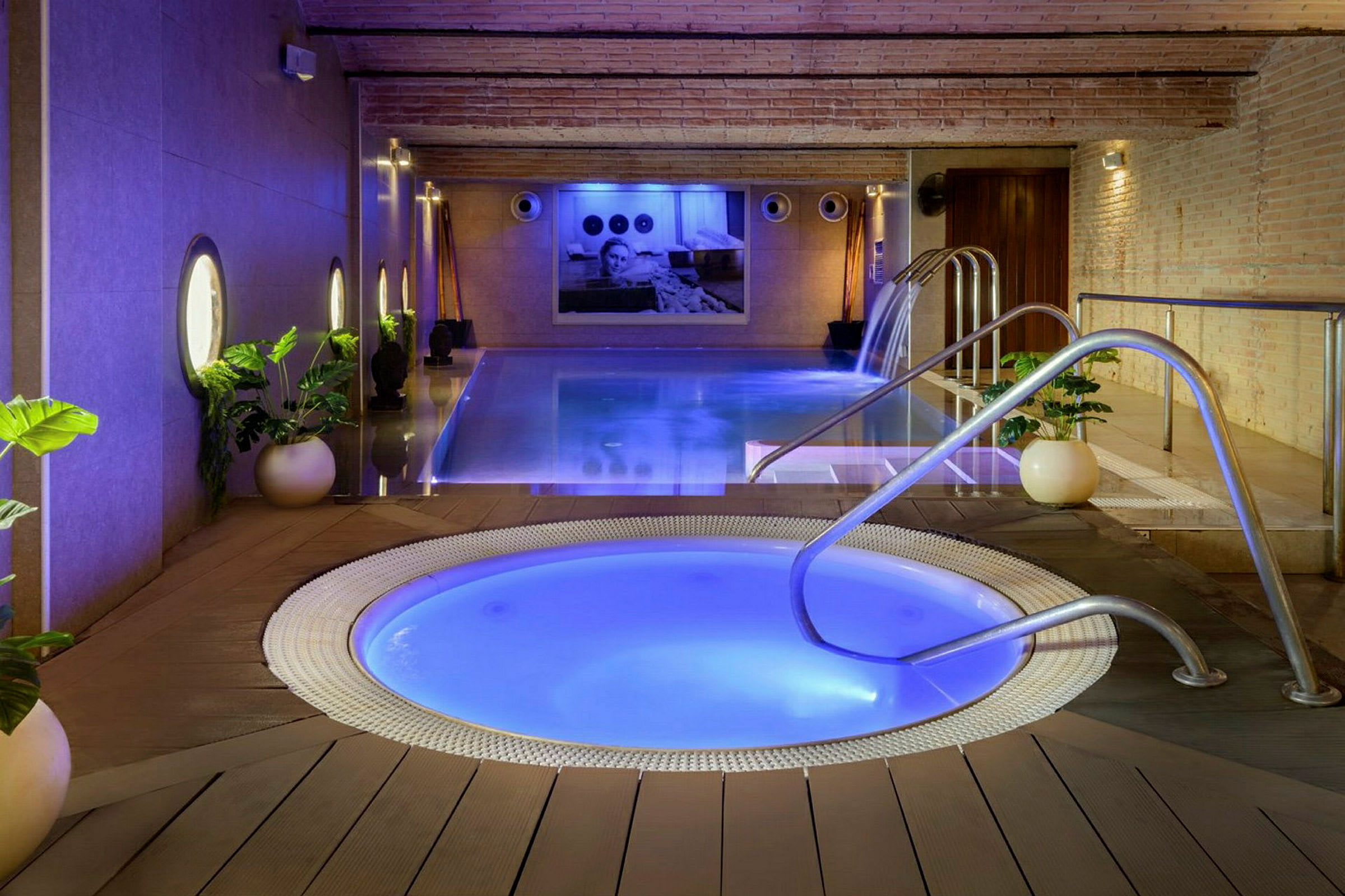 Bild av en avkopplande pool- och jacuzzimiljö inomhus, med växter och mjuk belysning. (AI-genererad text)