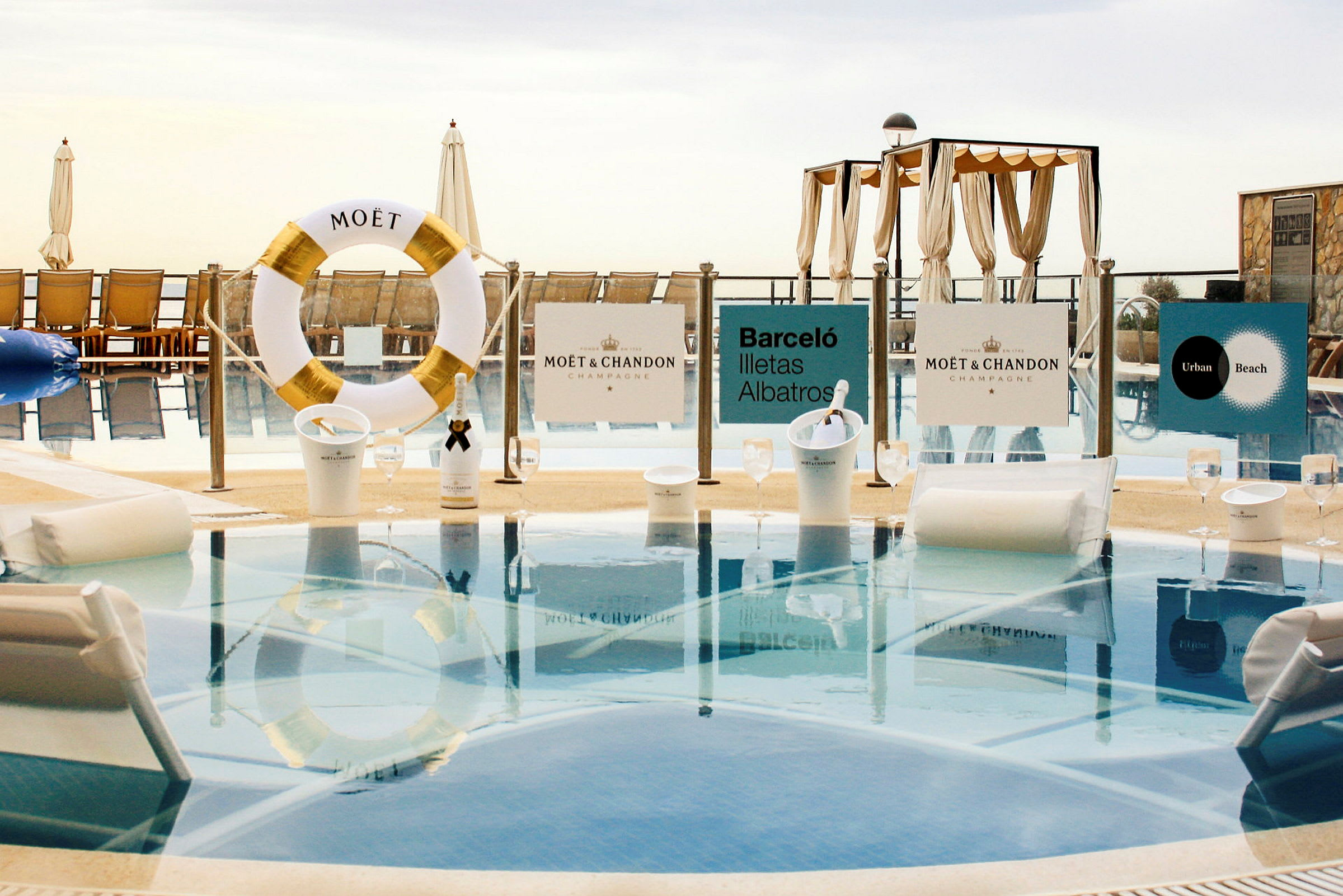 Bild av en lyxig pool med Moët & Chandon skyltar, solstolar och parasoller. (AI-genererad text)