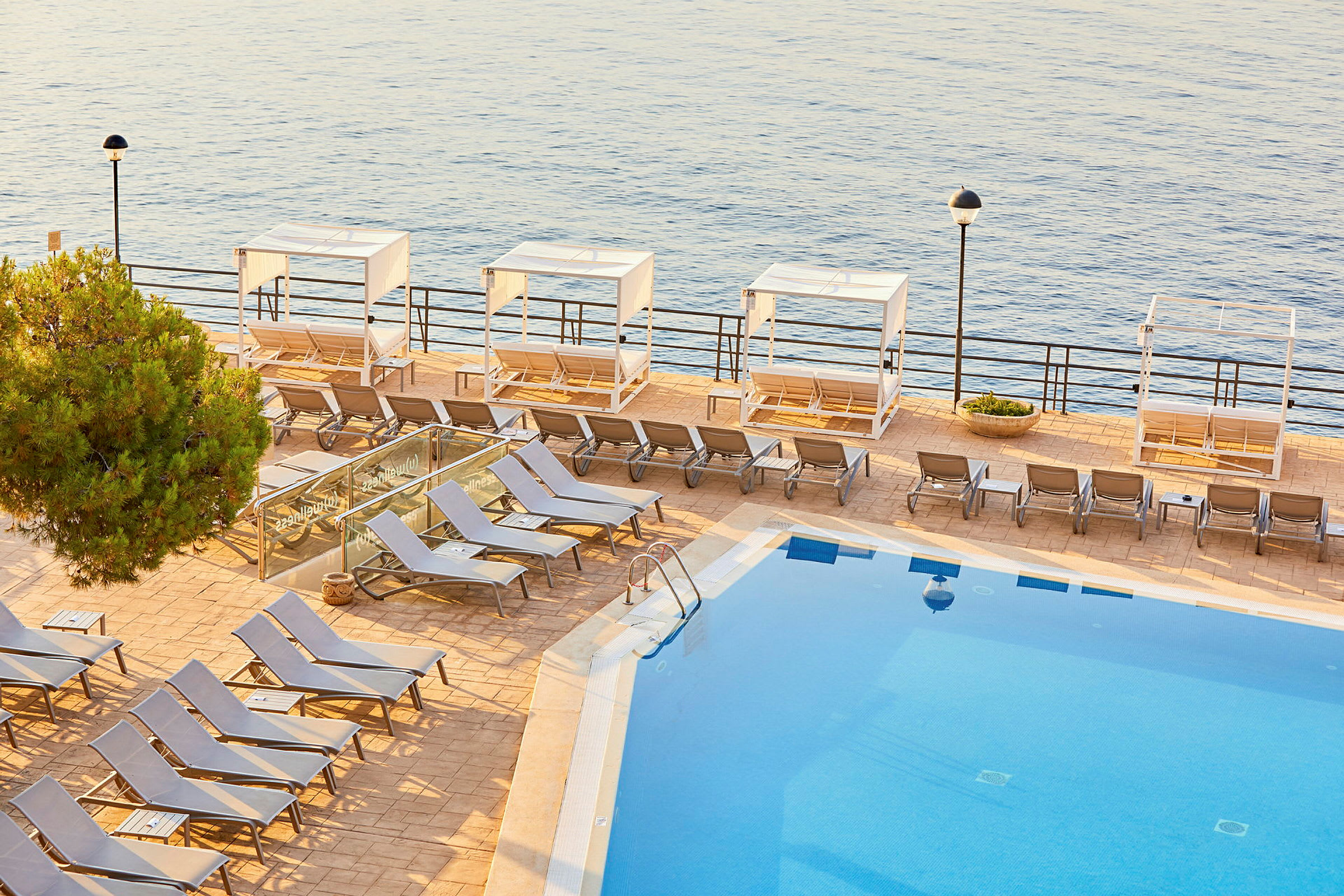 Utomhuspool med solstolar och cabana vid havet. (AI-genererad text)