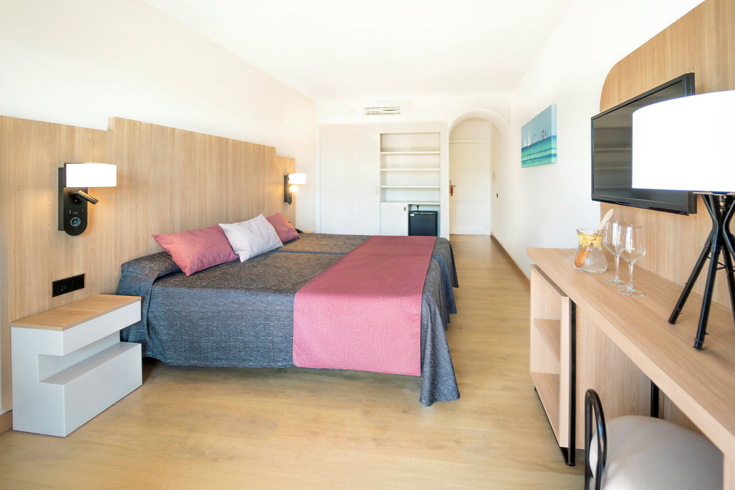 Ett hotellrum med två sängar, en modern inredning med trädetaljer, och en tv på väggen. (AI-genererad text)