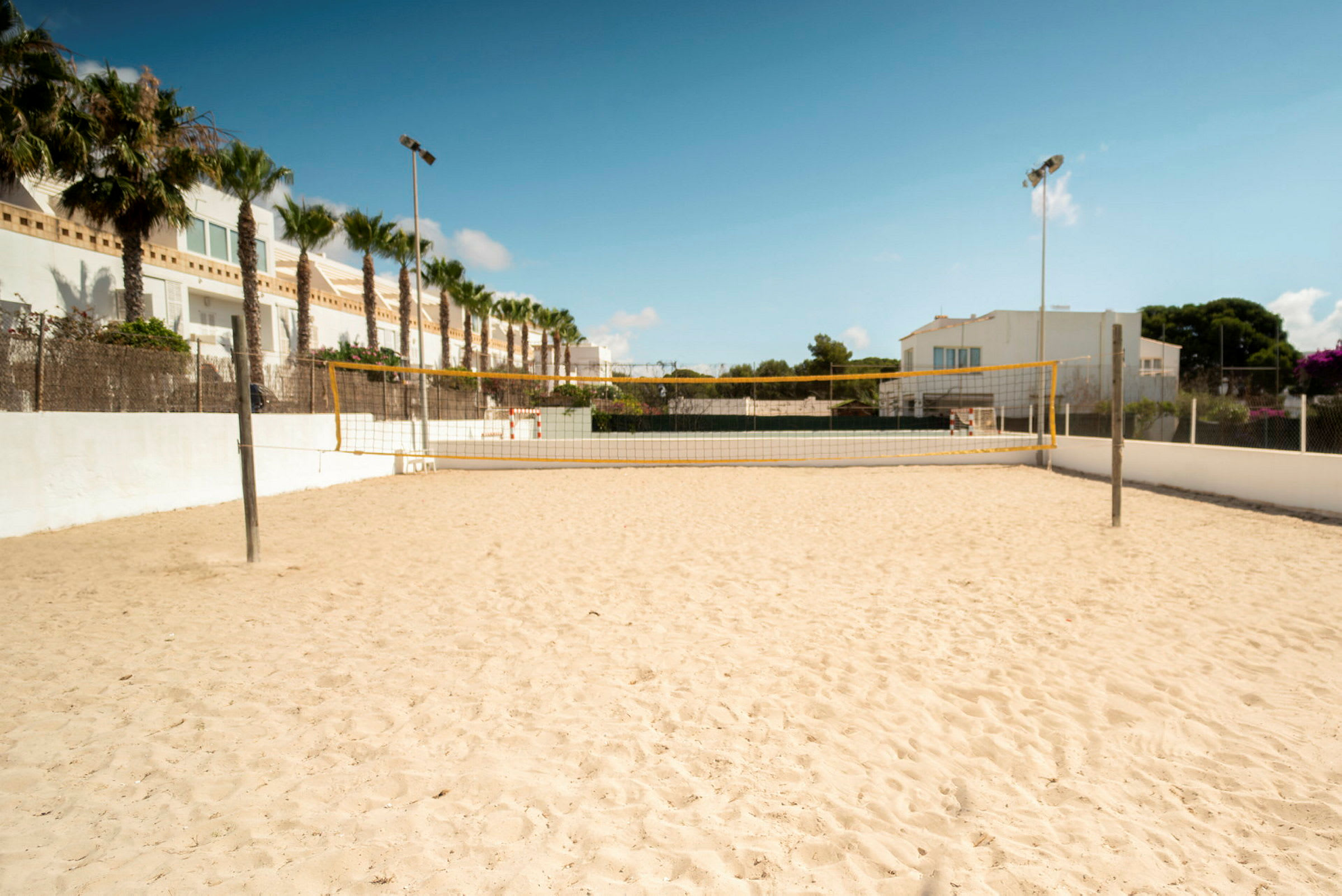 Sandplan med ett volleybollnät utomhus. (AI-genererad text)