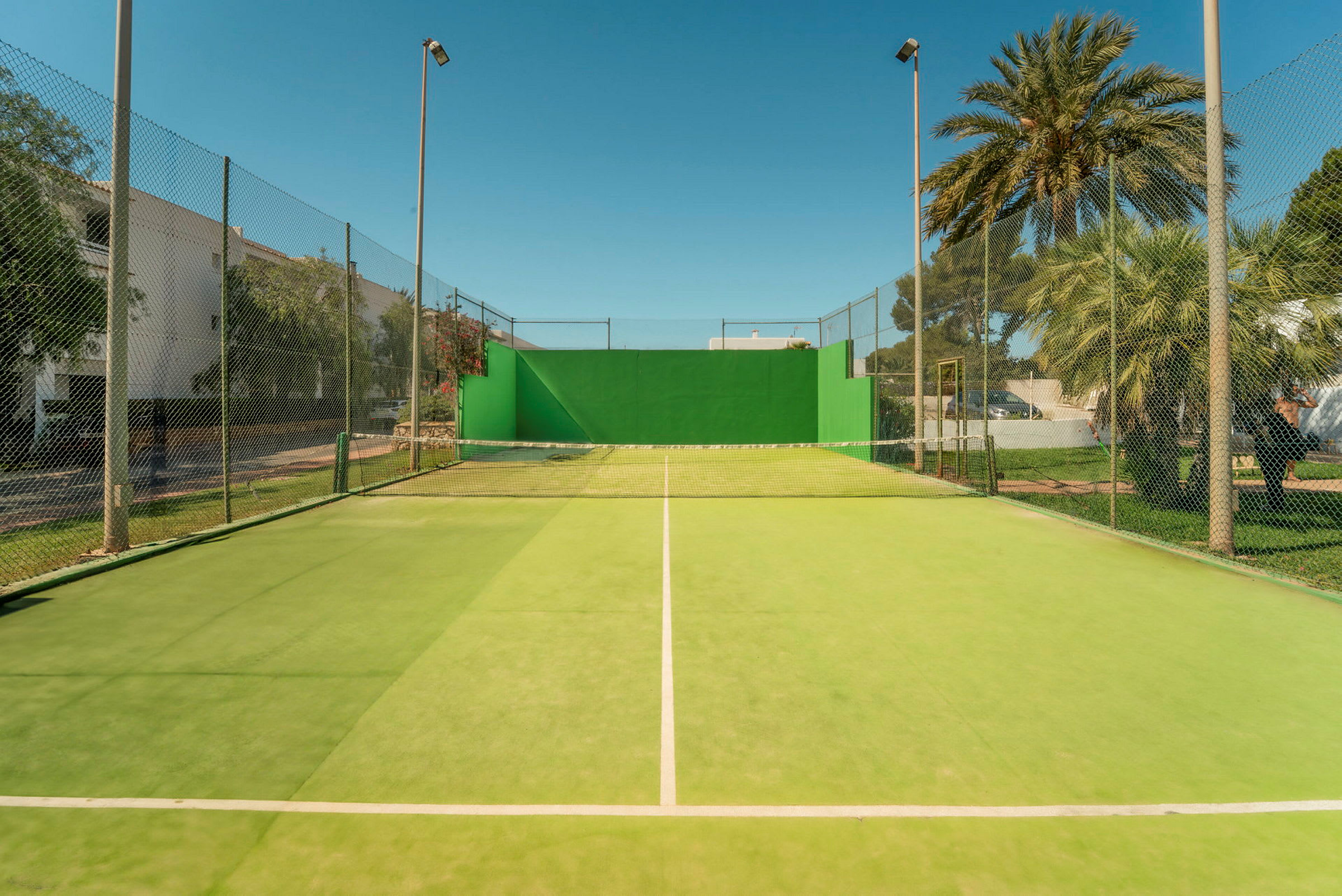 Tennisbana med grönt underlag och nät. (AI-genererad text)