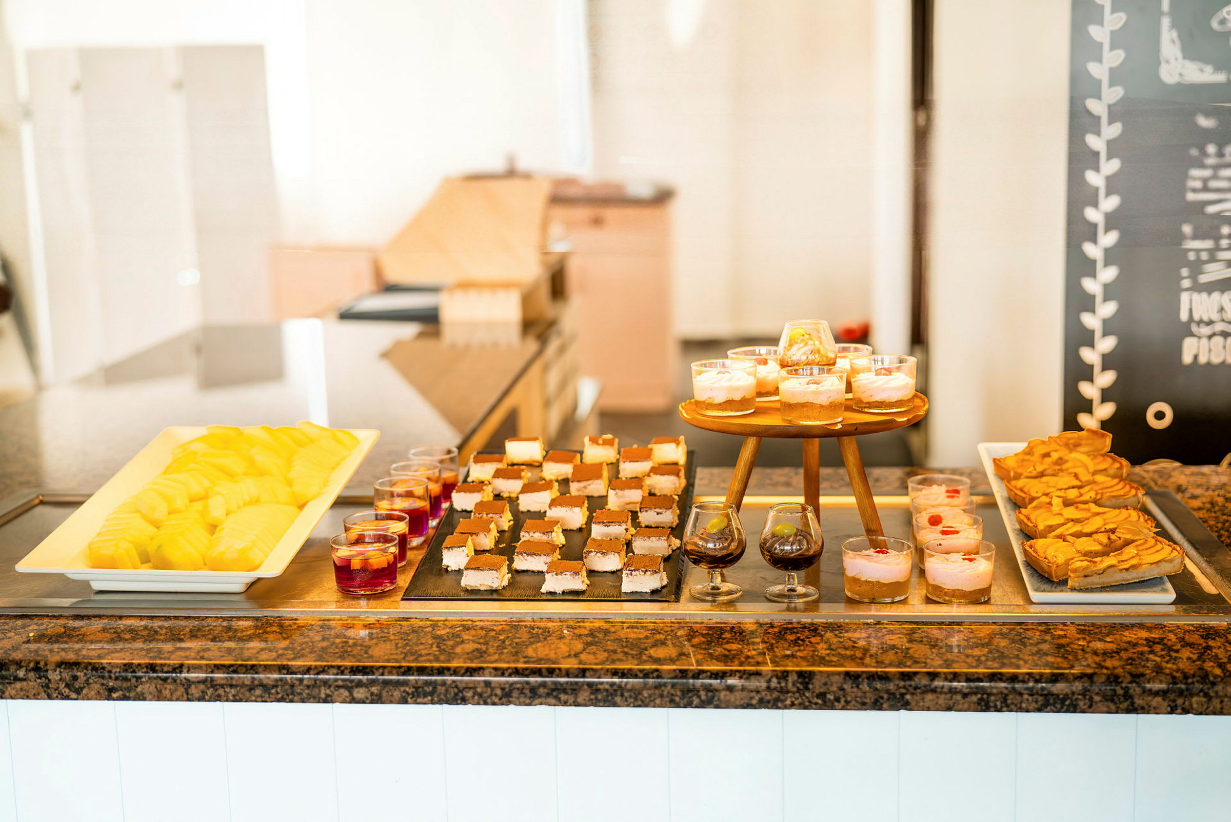 Buffé med olika desserter såsom skuren frukt, bakverk och dessert i glas. (AI-genererad text)