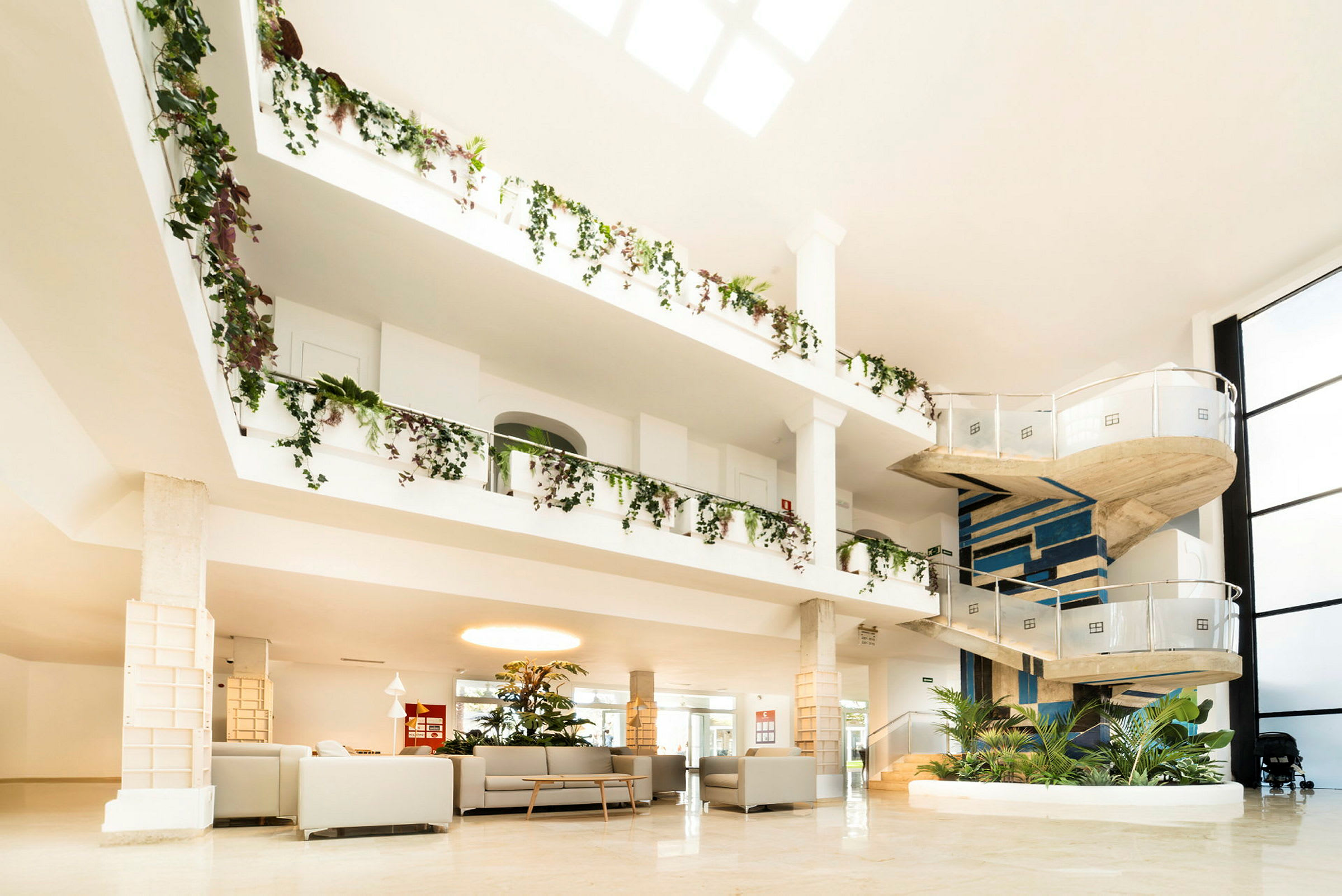 Interiör av rymligt hotell med en spiraltrappa och grönskande dekorationer. (AI-genererad text)