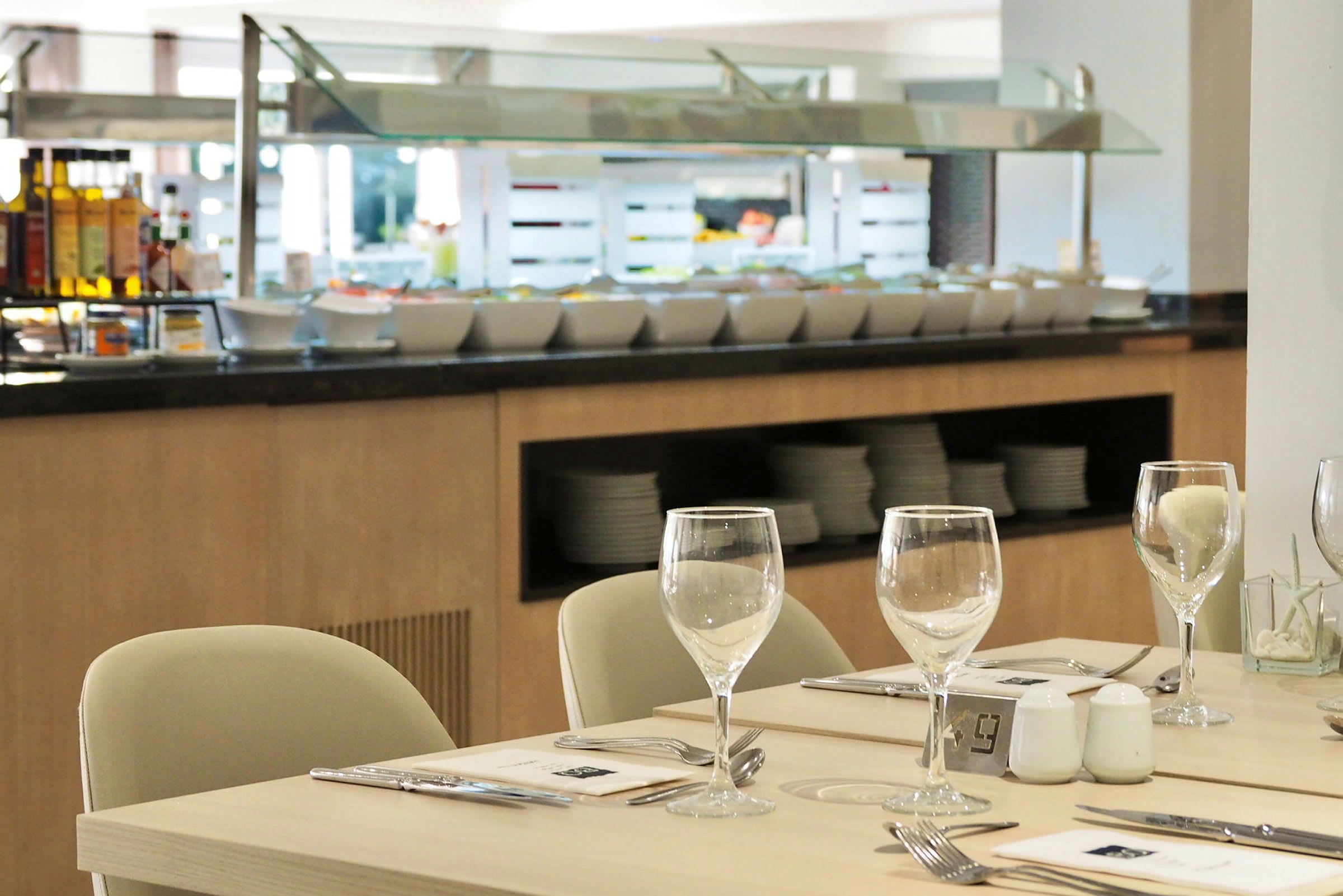 En restaurangbuffé med sittplatser och dukade bord i förgrunden. (AI-genererad text)
