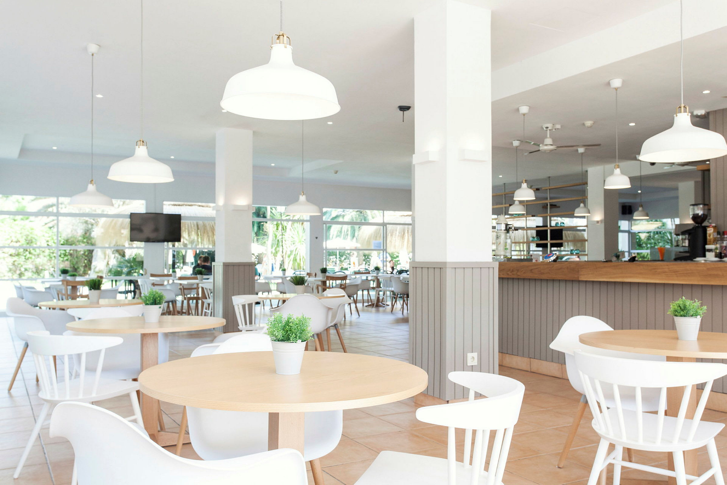Bild av en modern, ljus restaurang med bord, stolar och dekorativa växter. (AI-genererad text)