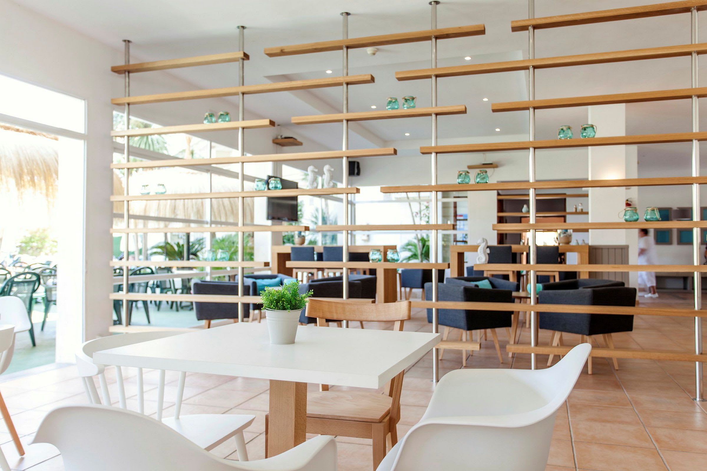 En ljus och modern restaurang med vita bord, trästolar och dekorativa hyllor. (AI-genererad text)