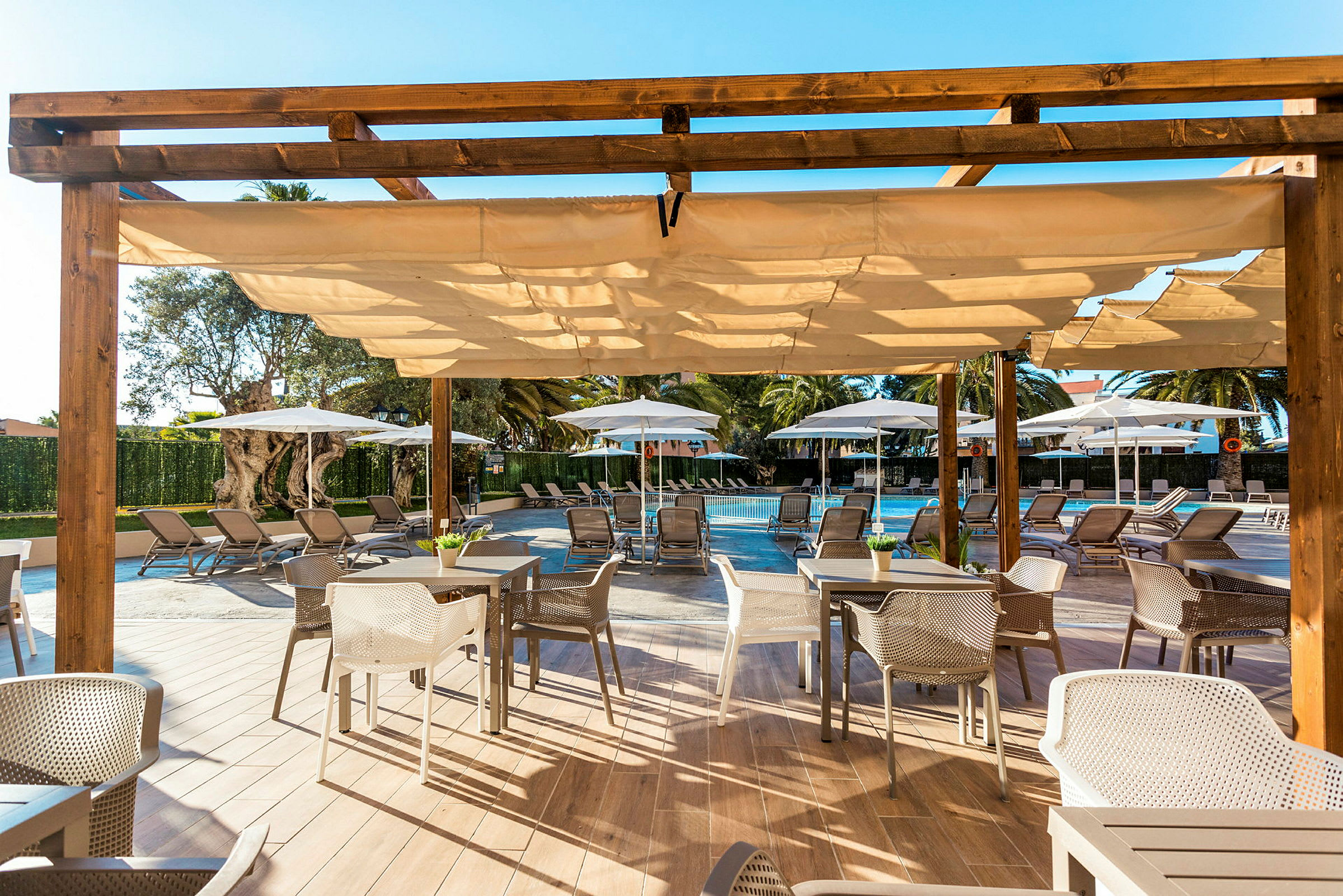 Uteservering med stolar och bord under en pergola, framför en pool och solstolar. (AI-genererad text)