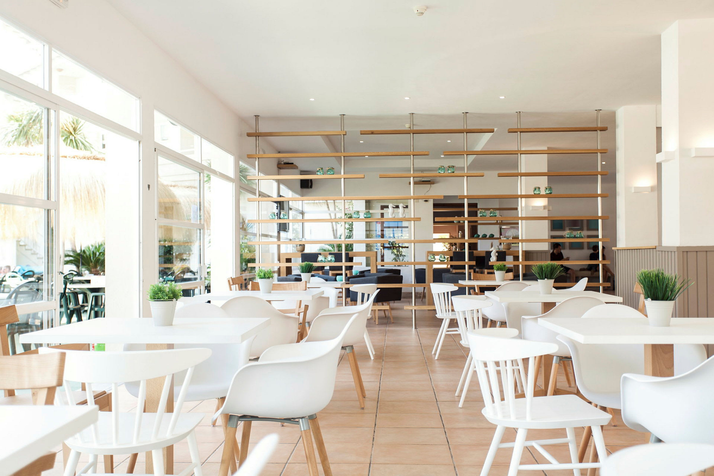 Ljus och modern restaurang med vita möbler och gröna växter. (AI-genererad text)
