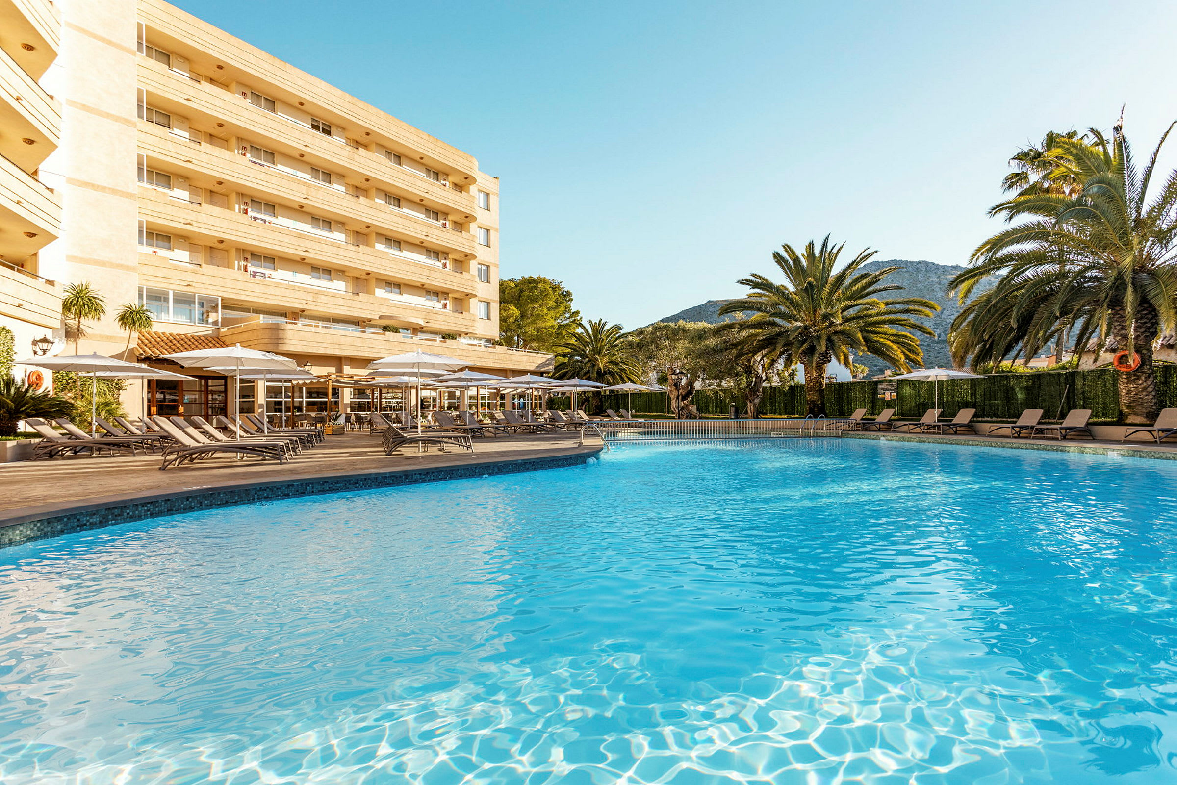 Bild av en pool med solstolar och ett hotell i bakgrunden. (AI-genererad text)