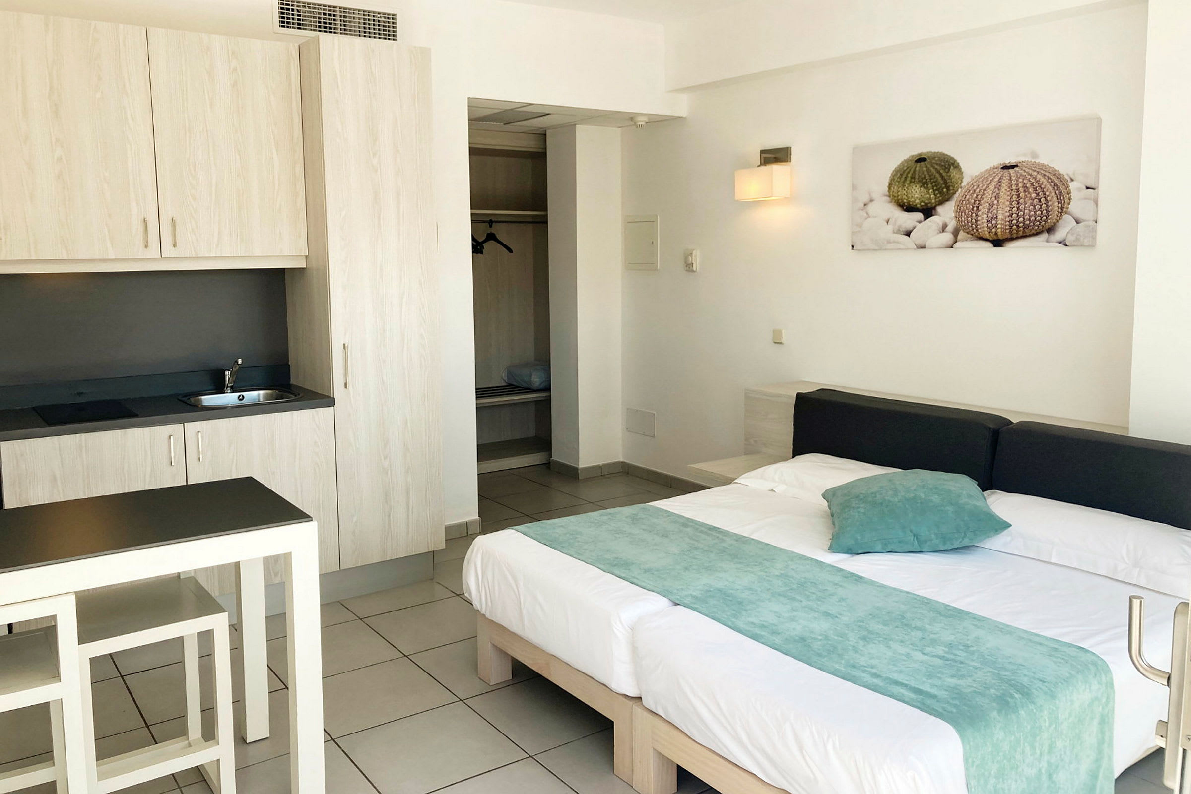Bild av ett hotellrum med en säng, ett litet kök och en garderob. (AI-genererad text)