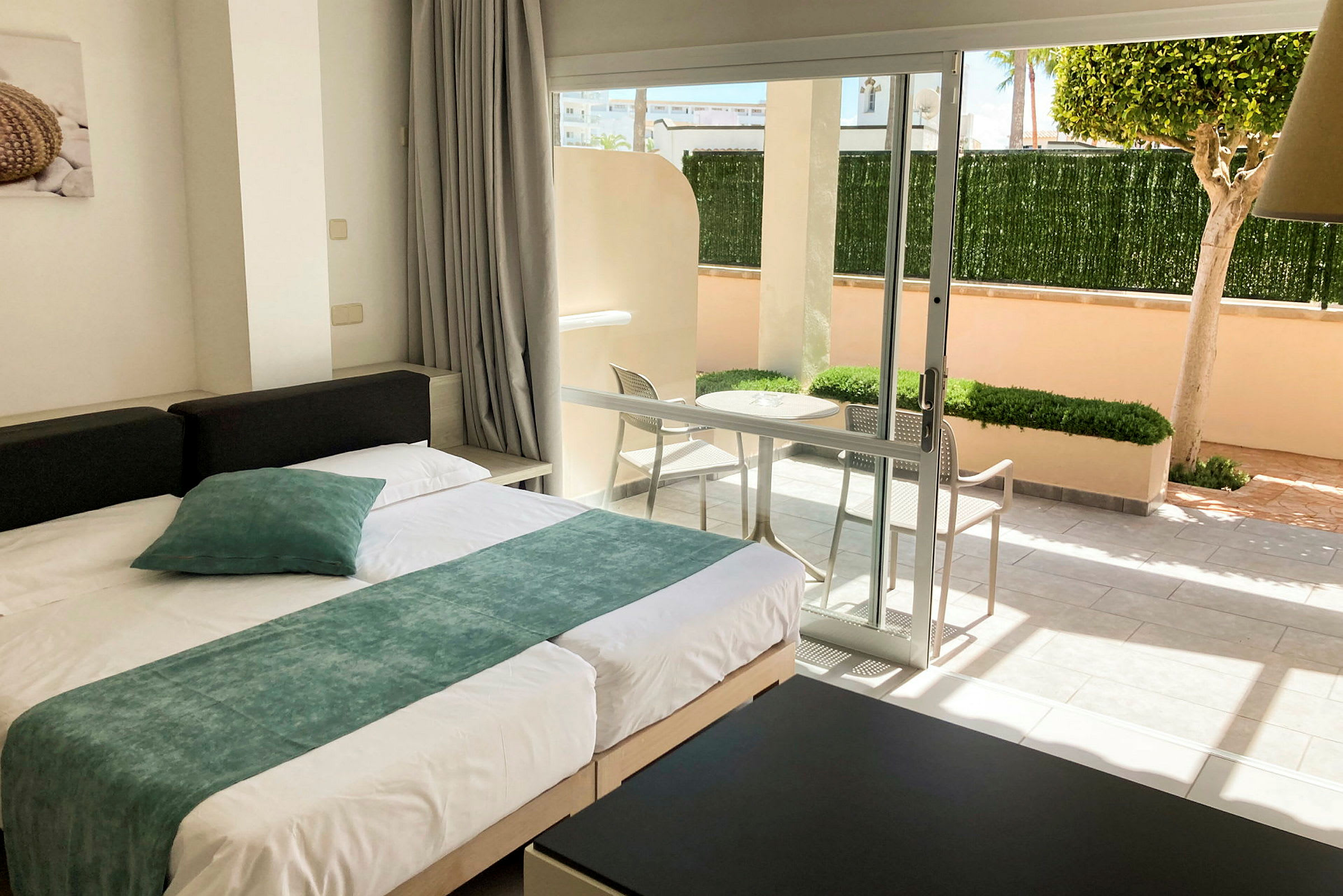 Modernt inrett hotellrum med säng och utsikt mot en privat terrass. (AI-genererad text)
