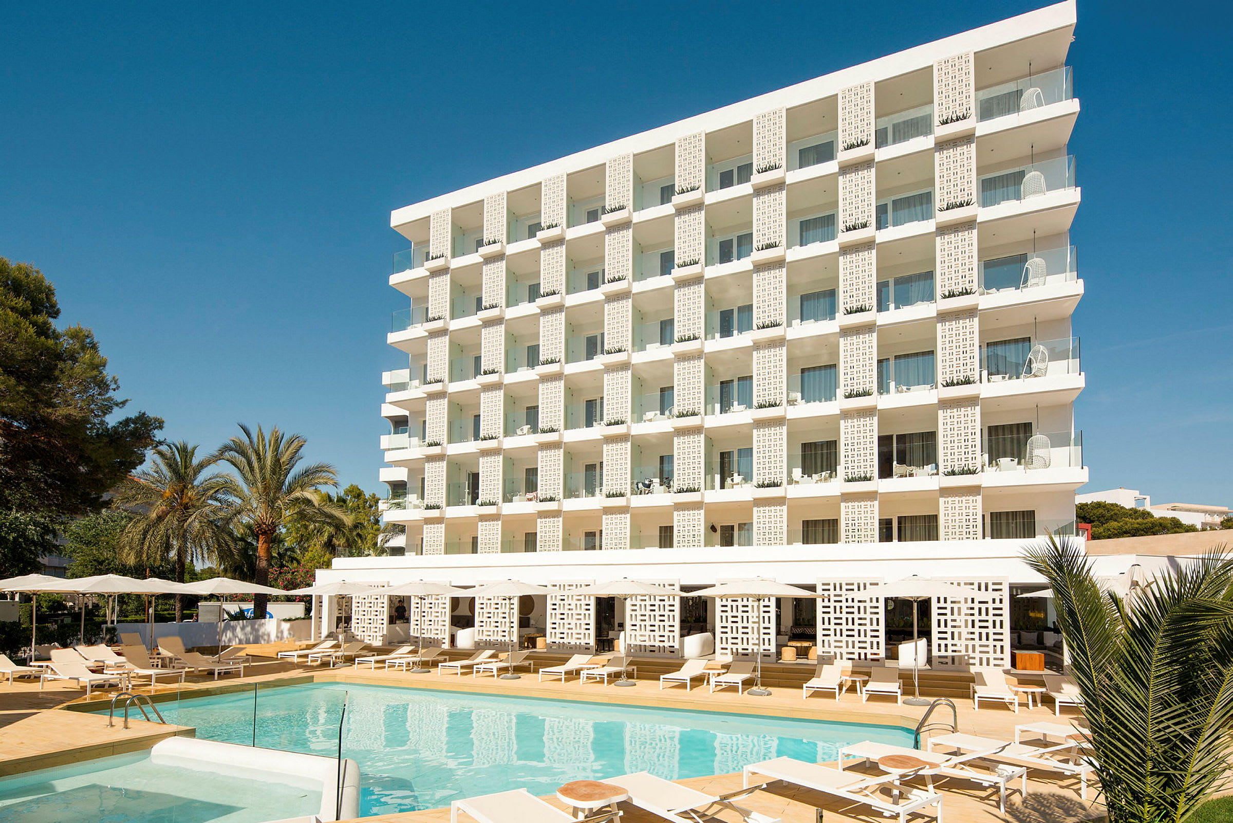 Hotellbyggnad med balkonger framför en poolområde. (AI-genererad text)