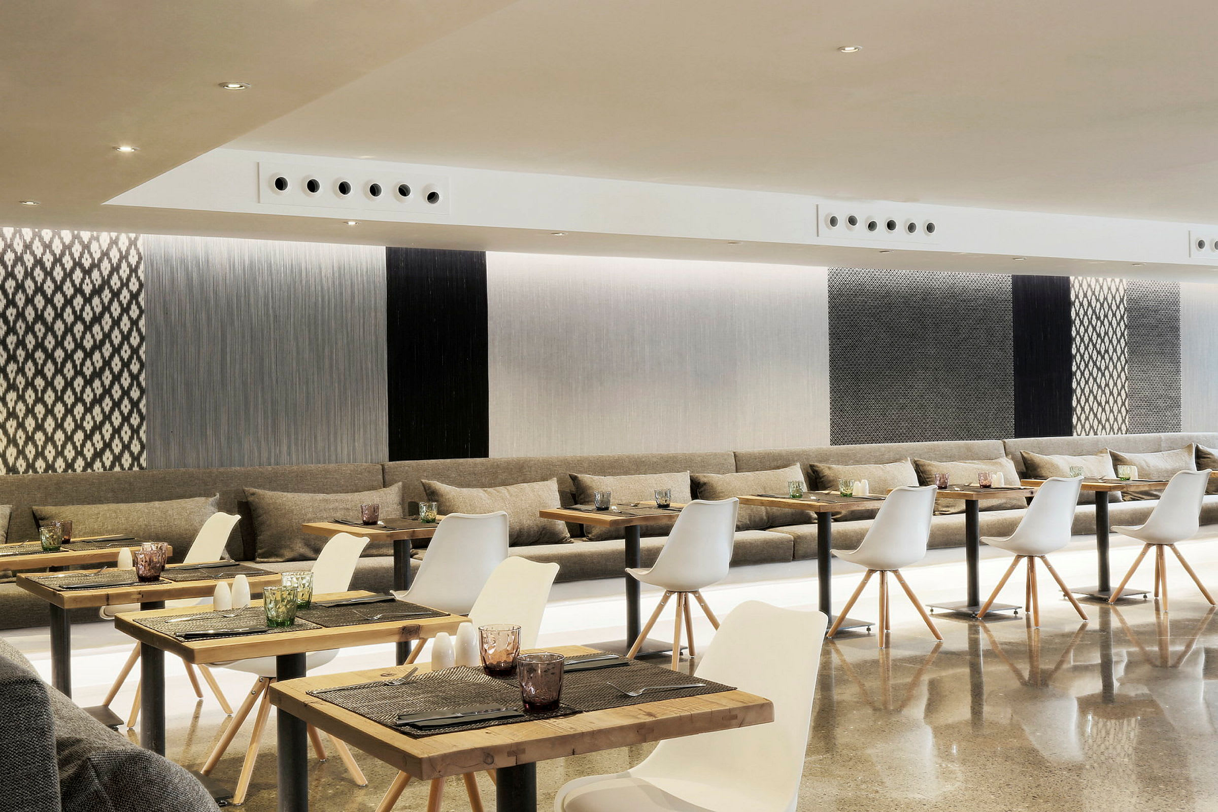 En modern restaurang med vita stolar och bord, samt en inredning med texturerade väggpaneler. (AI-genererad text)