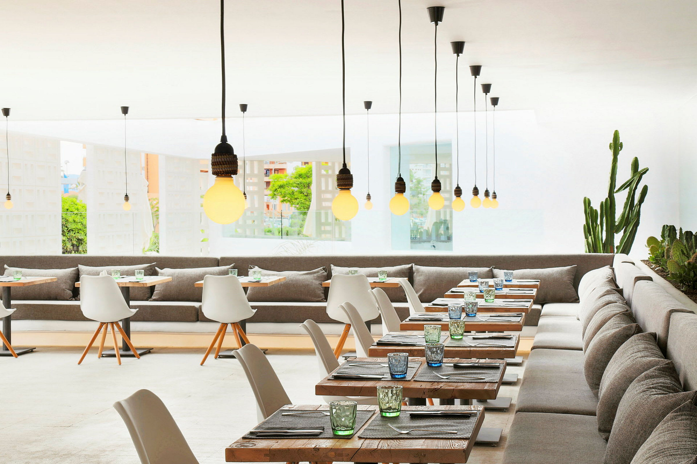 Restaurang med modern inredning, bord och stolar samt hängande lampor. (AI-genererad text)