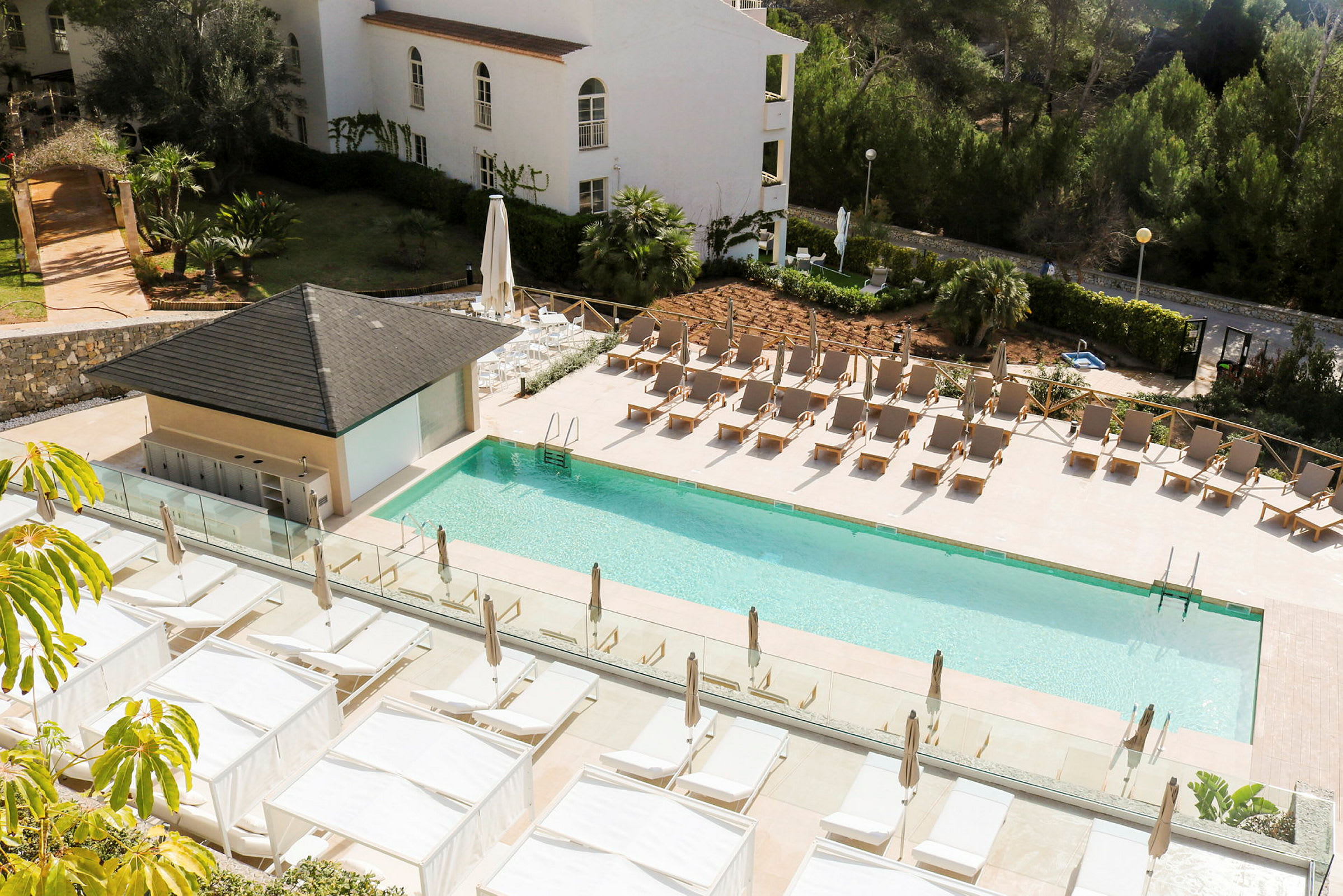 Utomhuspool med solstolar och baldakiner vid ett hotell. (AI-genererad text)