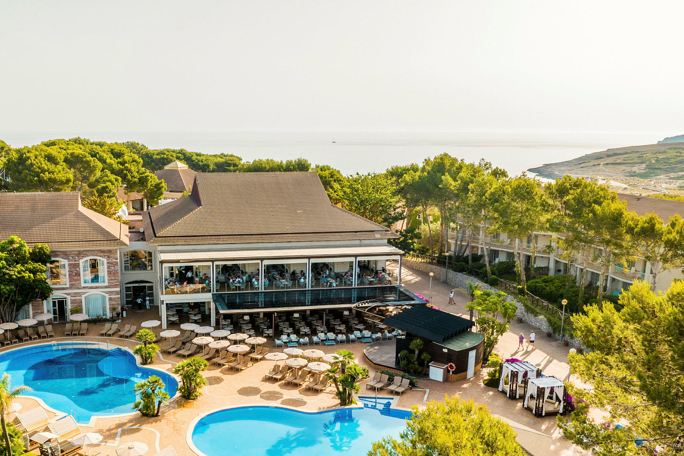 Bild av en resort med flera byggnader, swimmingpooler och omgivande grönska. (AI-genererad text)