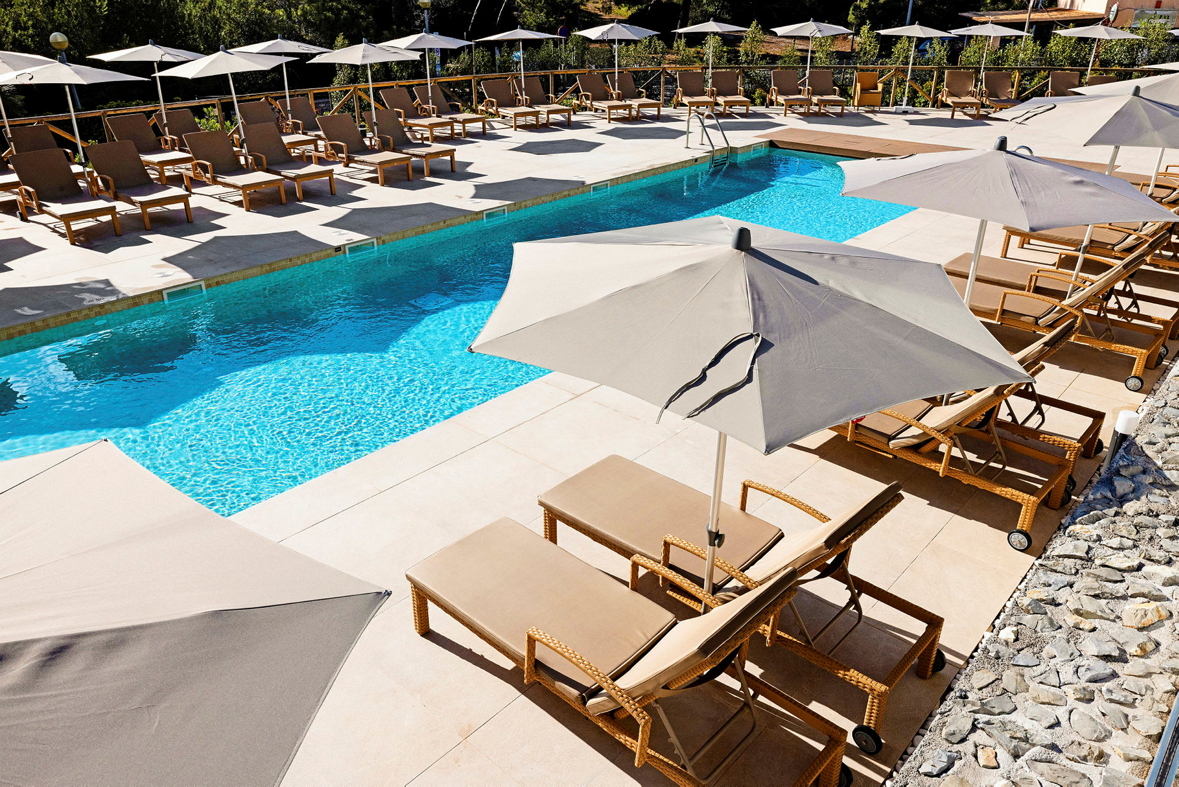 En swimmingpool med solstolar och parasoller vid sidan. (AI-genererad text)