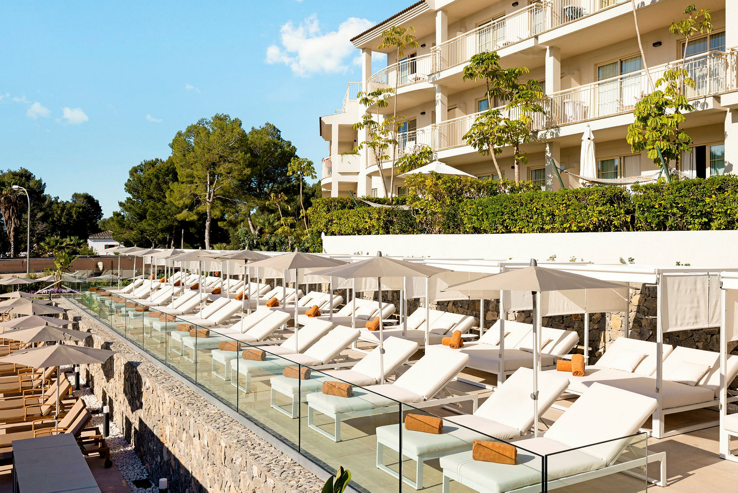 Solstolar med parasoller vid en pool intill ett hotell. (AI-genererad text)