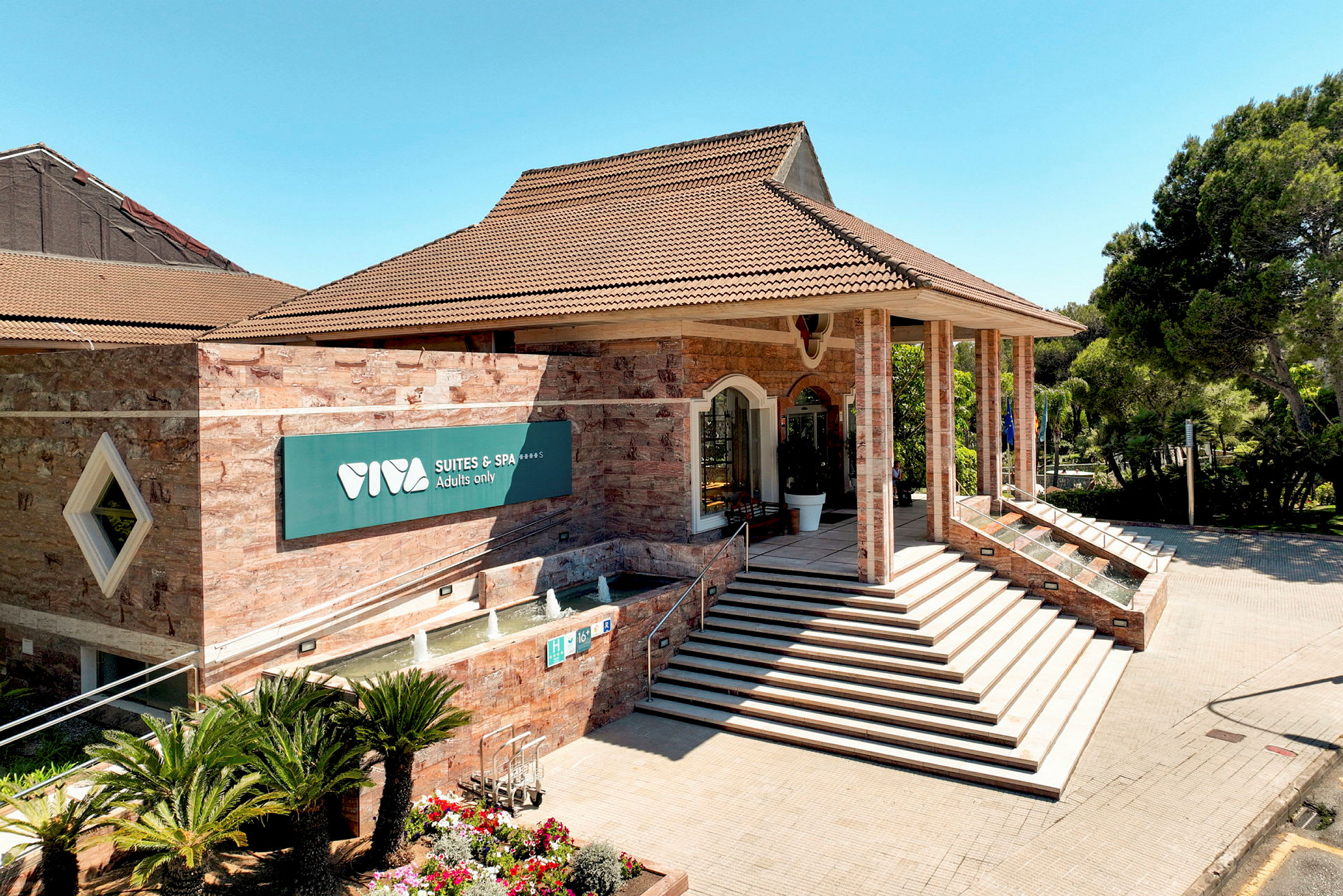 Entré till Viva Suites & Spa med trappor och fontän. (AI-genererad text)