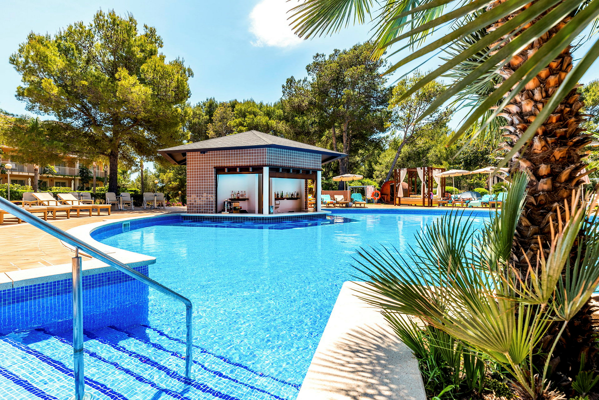 Utomhuspool med träd och en poolbar i bakgrunden. (AI-genererad text)