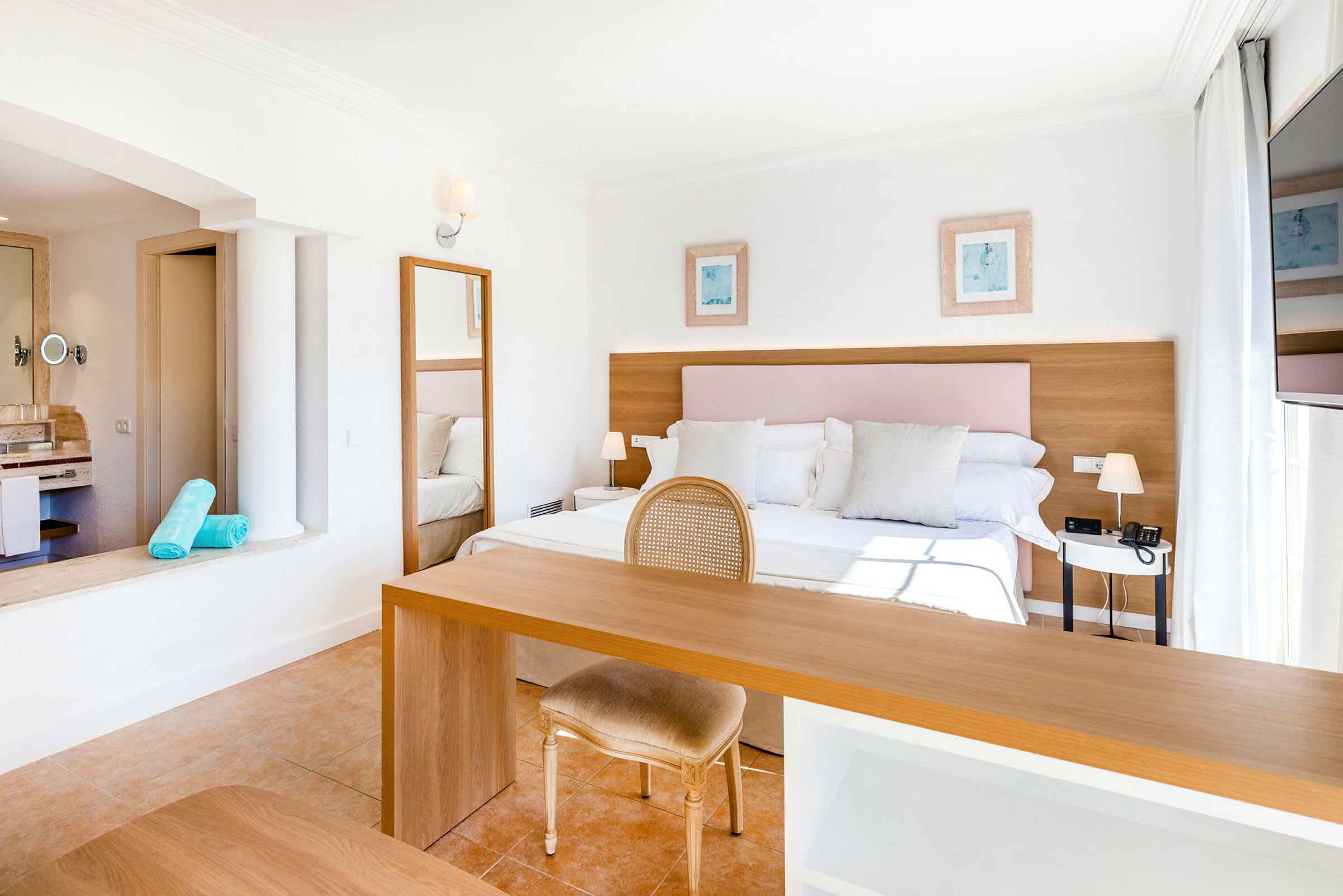 Ljust och rymligt hotellrum med dubbelsäng, skrivbord och stol. (AI-genererad text)