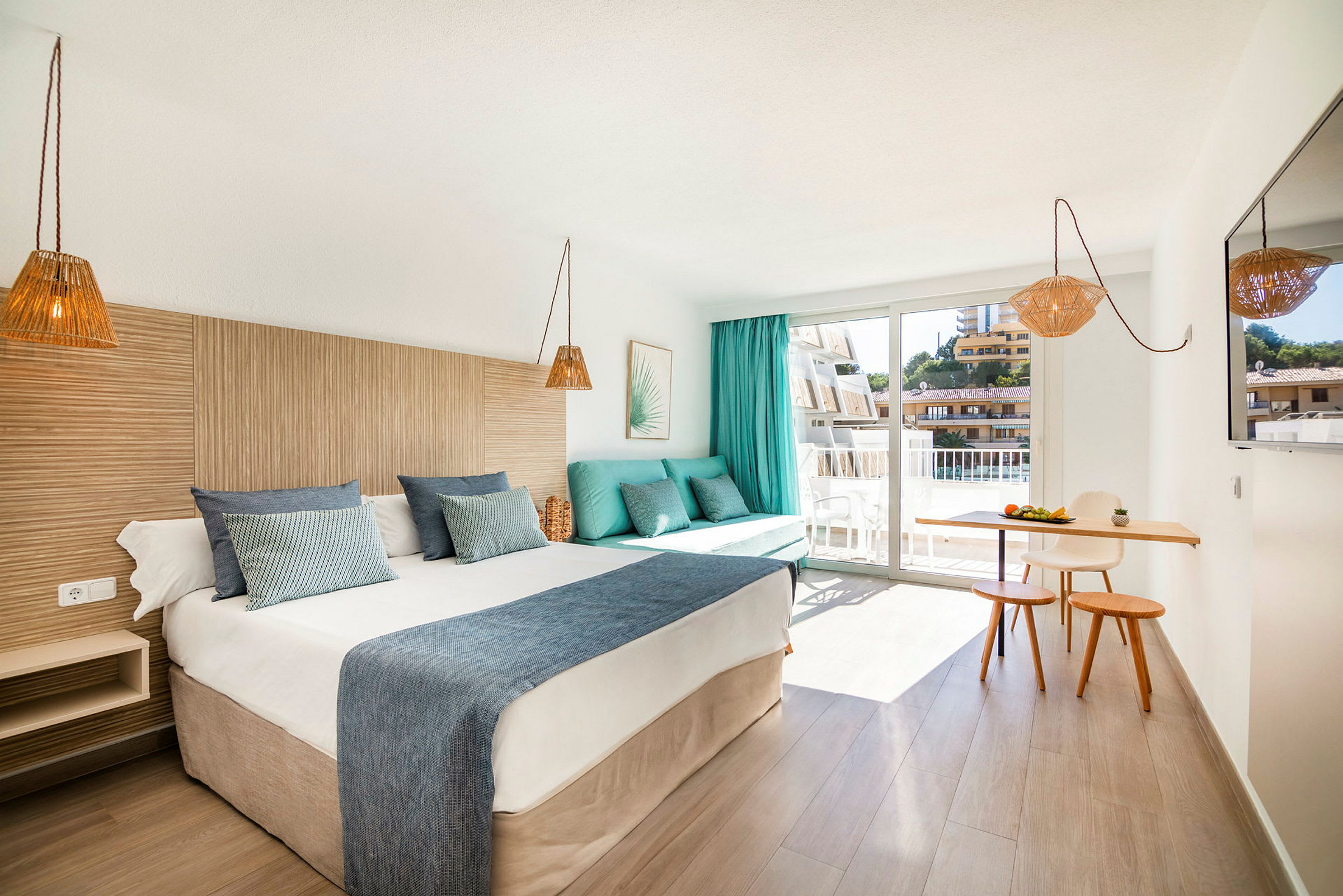 Hotellrum med en dubbelsäng, en soffa med kuddar, en liten matplats och en balkong. (AI-genererad text)