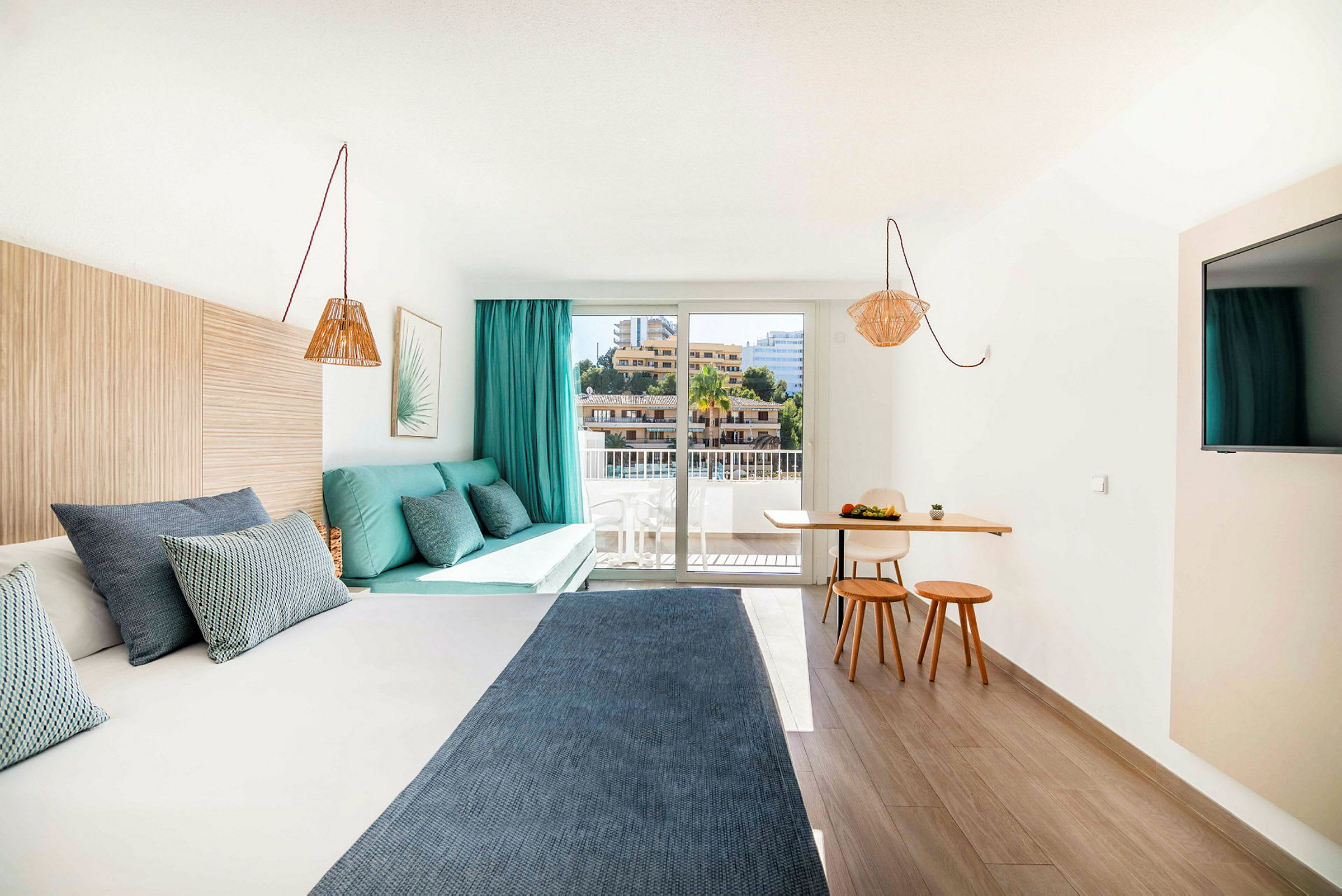 Ett modernt hotellrum med en säng, en sittgrupp och en liten matplats vid ett stort fönster. (AI-genererad text)
