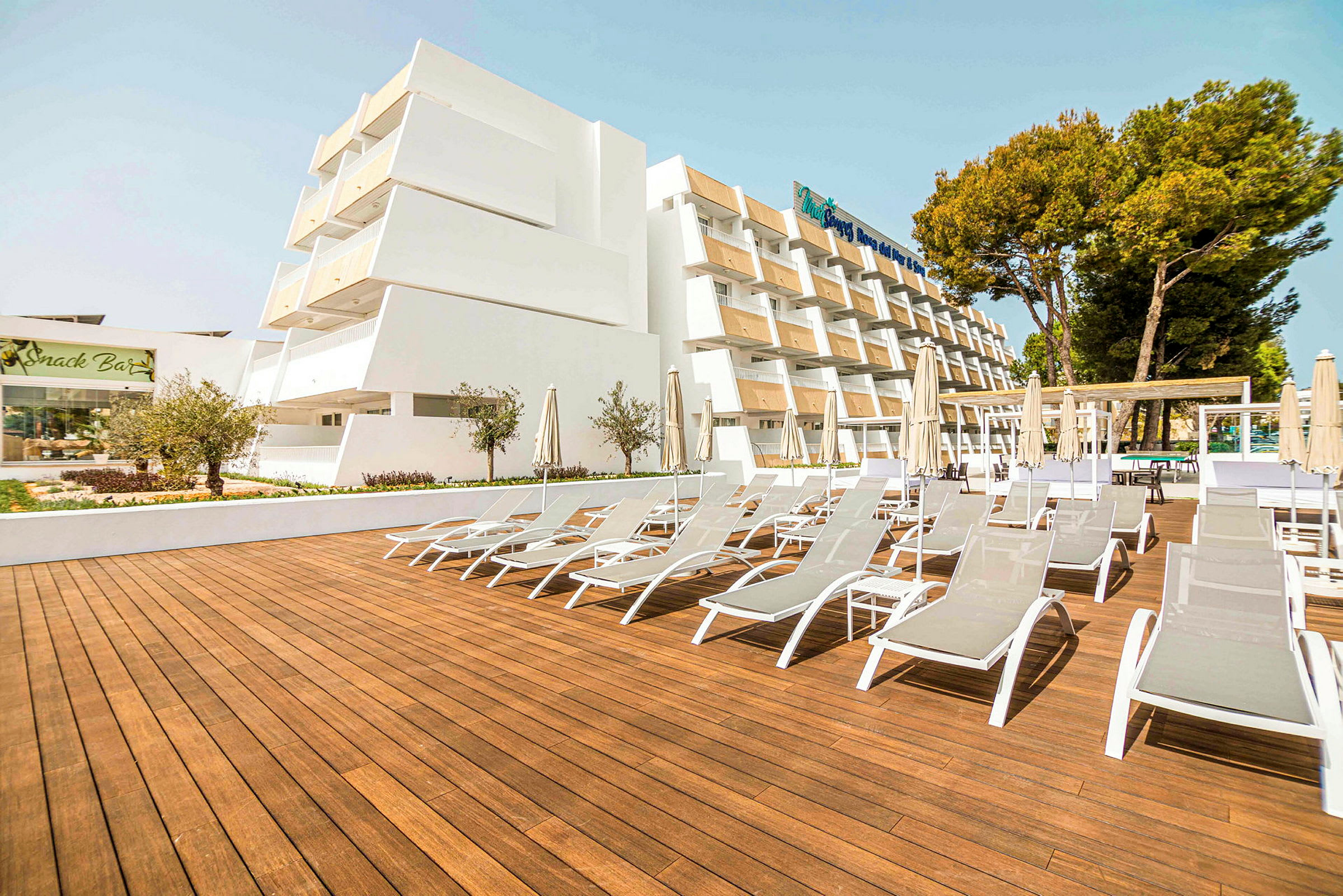 Bild av ett hotell med solstolar på en träterrass. (AI-genererad text)