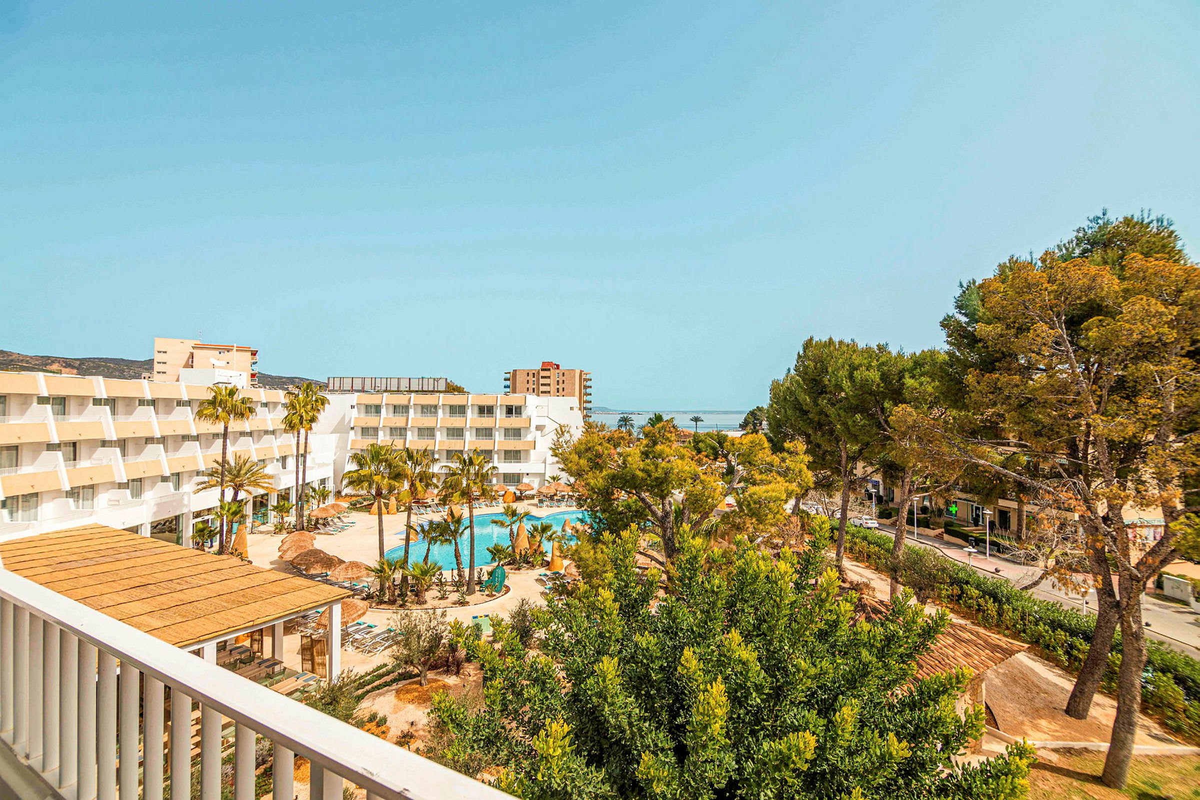 Utsikt över hotellkomplex med pool, träd och omgivande byggnader. (AI-genererad text)