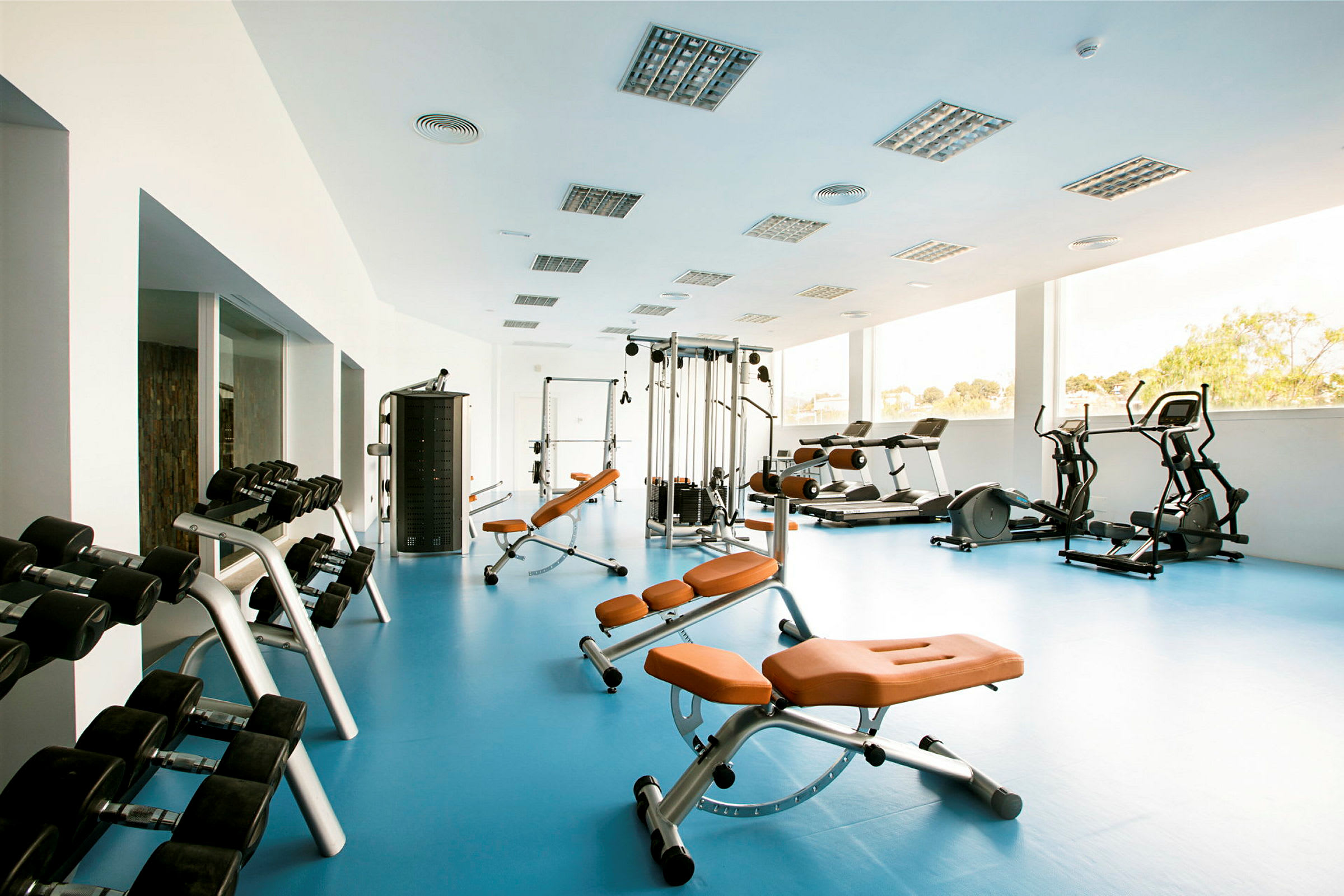 Ett gym med träningsutrustning såsom bänkar, vikter och konditionsmaskiner. (AI-genererad text)