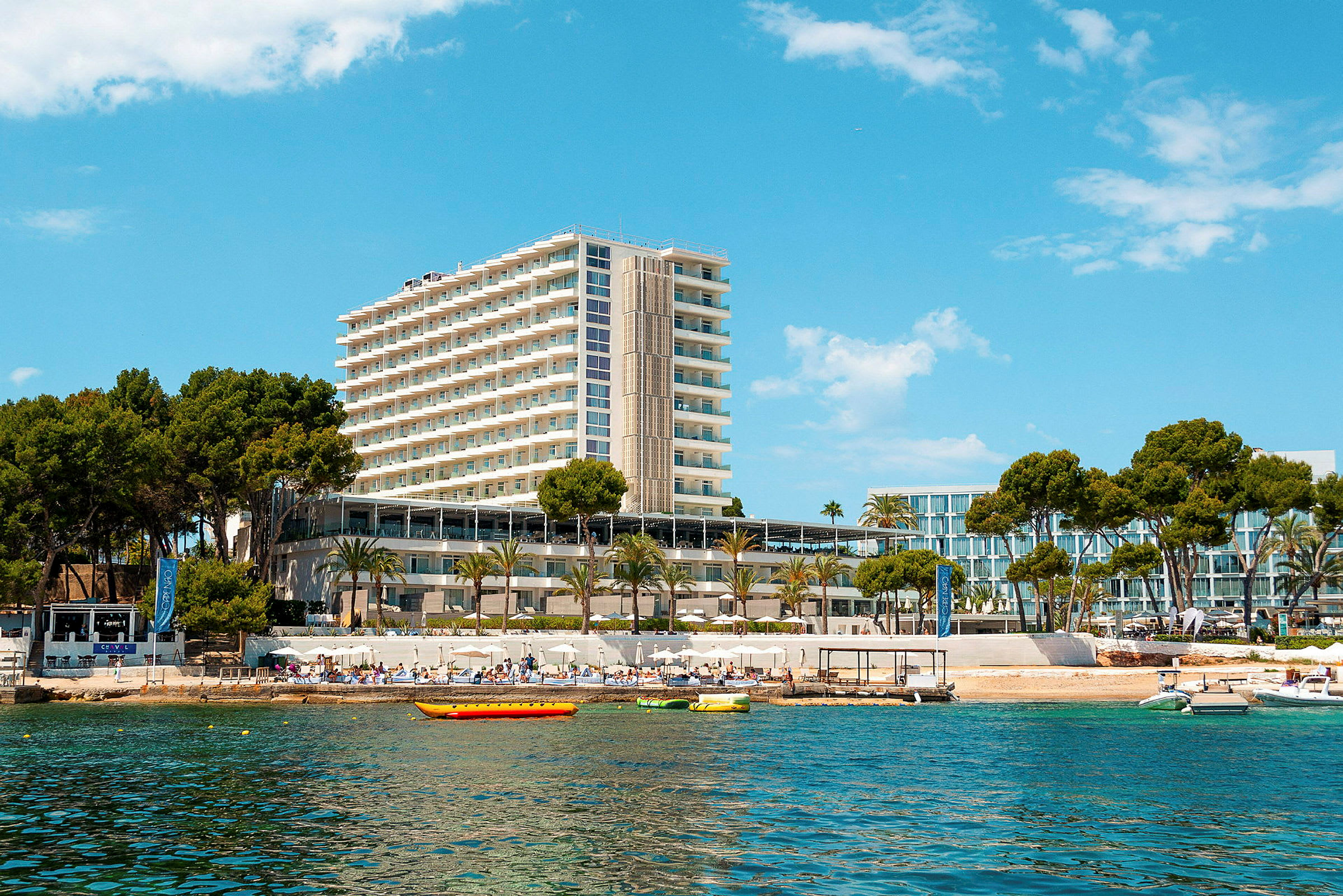 Högt hotell vid strand med klarblå himmel. (AI-genererad text)