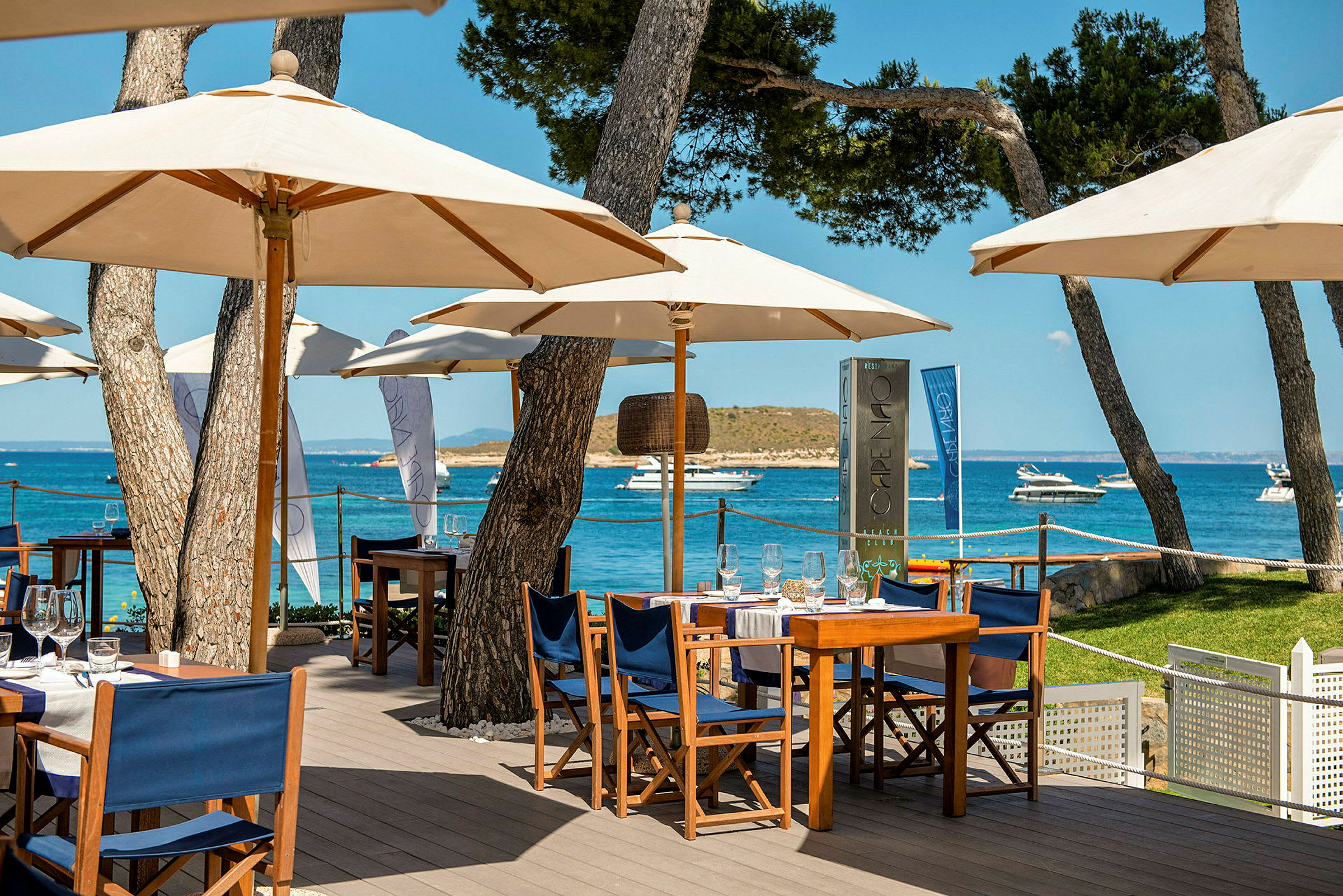 Utomhusrestaurang med parasoller och bord vid havet. (AI-genererad text)