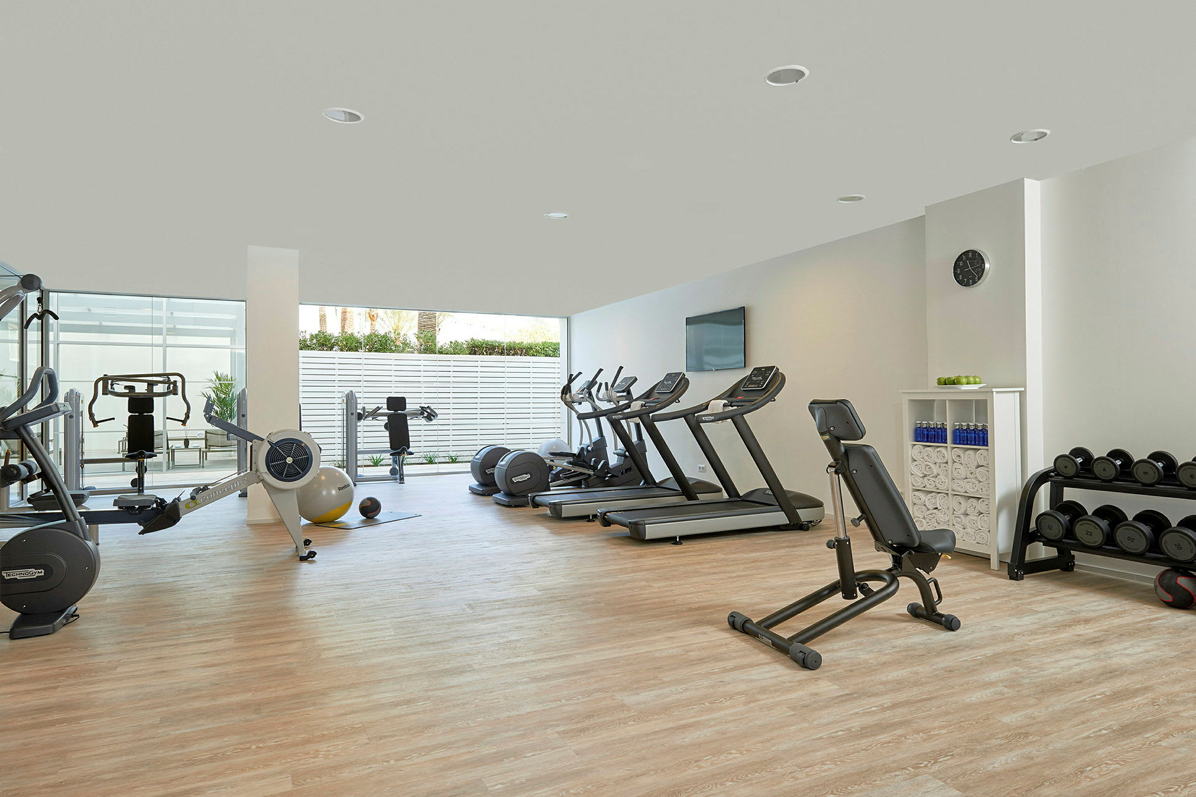 Ett gym med träningsmaskiner, löpband och vikter på ett öppet och ljust område. (AI-genererad text)