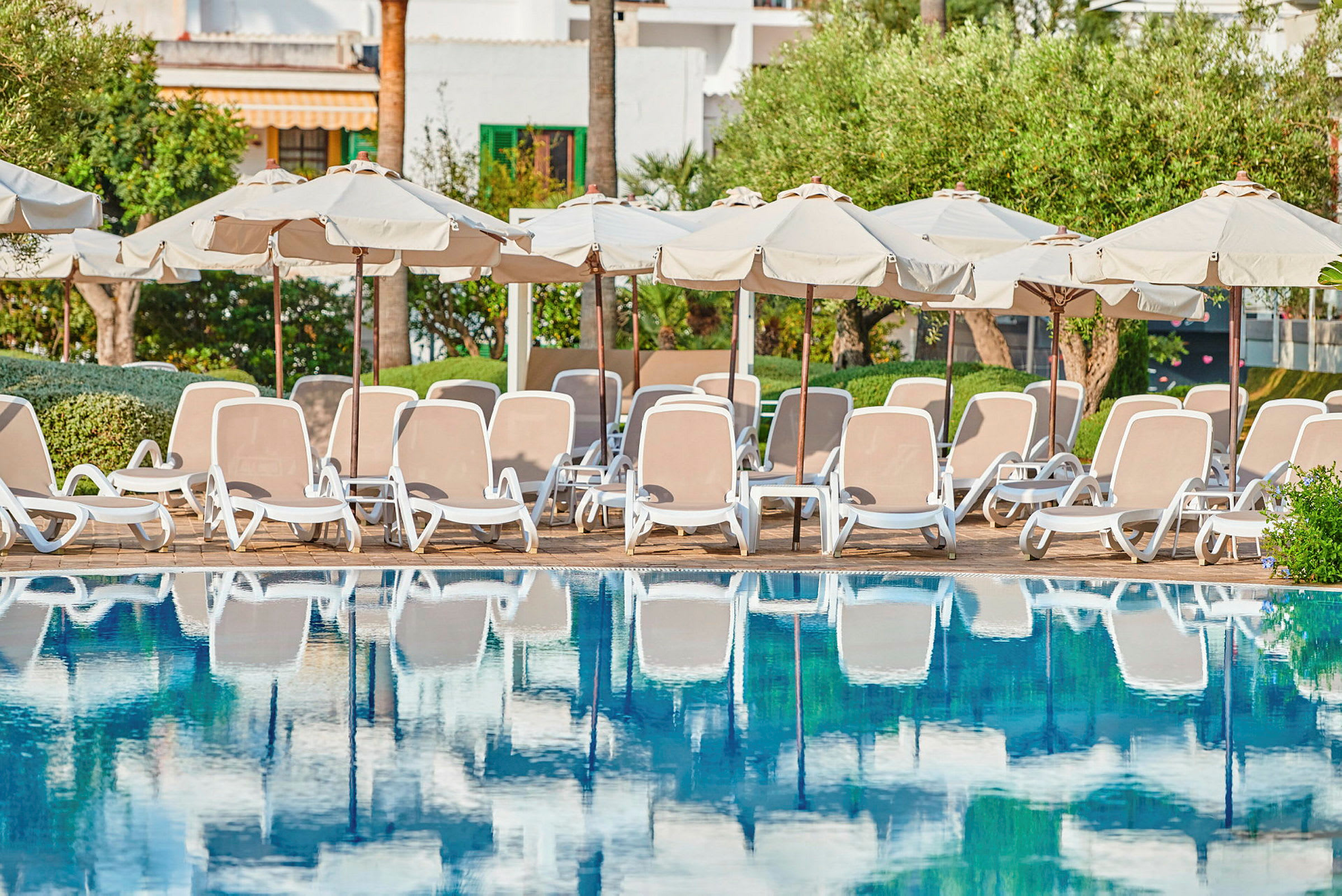 Solstolar och parasoller vid kanten av en pool. (AI-genererad text)