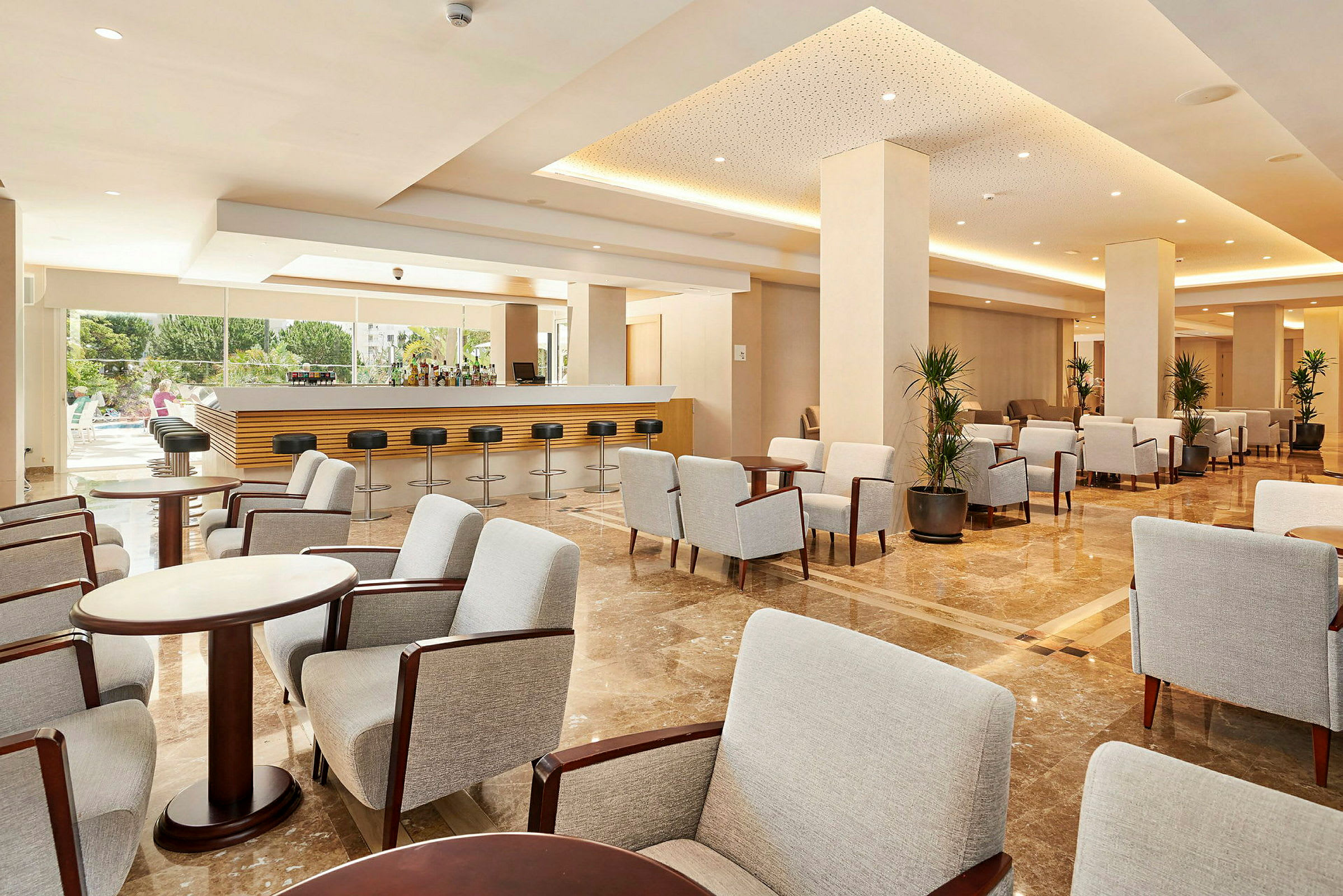 Elegant hotellounge med bekväma gråa stolar och soffbord, samt bar med höga stolar. (AI-genererad text)
