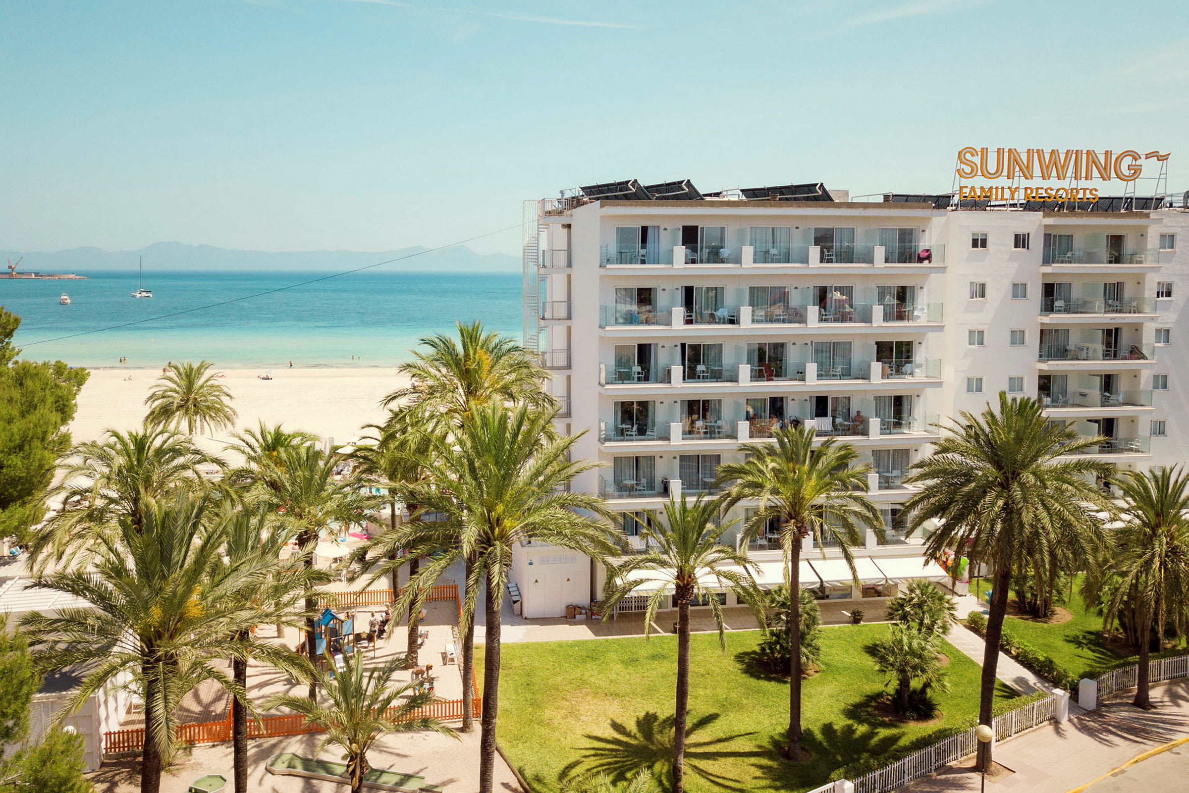 Bild av en hotellbyggnad vid stranden, omgiven av palmer. (AI-genererad text)