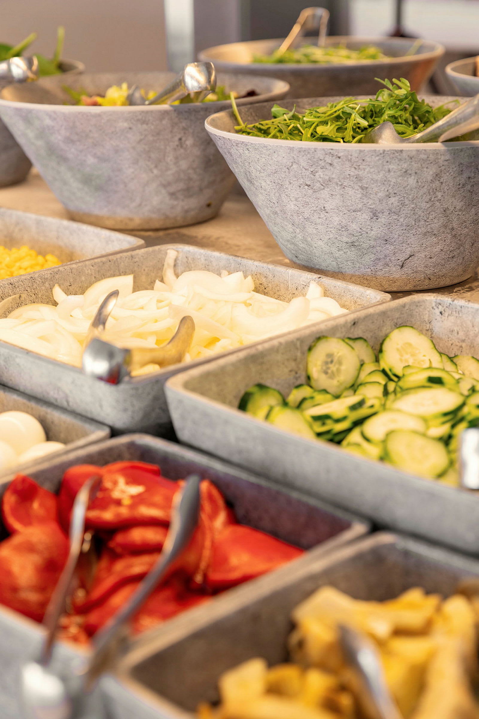 En salladsbuffé med olika grönsaker och tillbehör i skålar. (AI-genererad text)