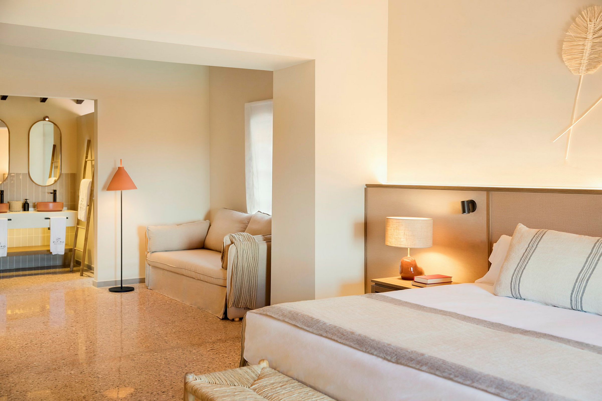 Ett stilrent hotellrum med en säng, soffa och ett öppet badrum. (AI-genererad text)