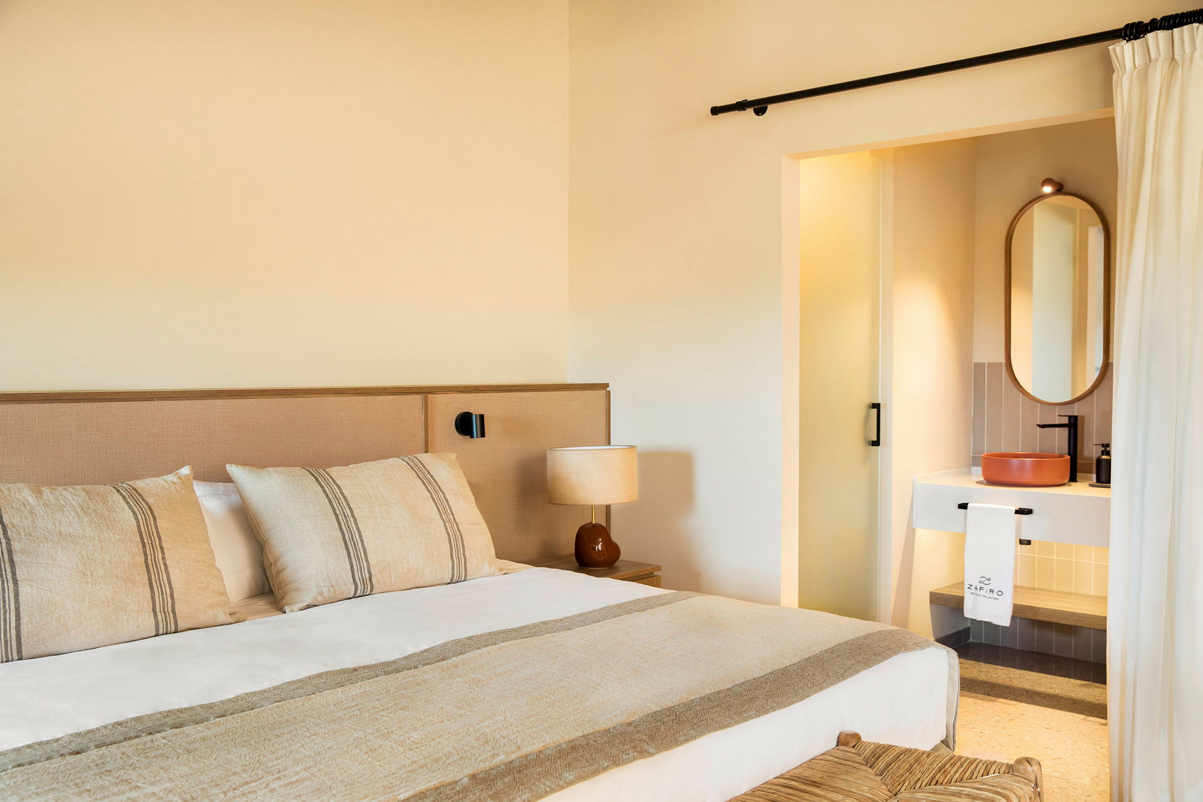 Ett hotellrum med en säng, lampbord och en synlig del av ett badrum. (AI-genererad text)
