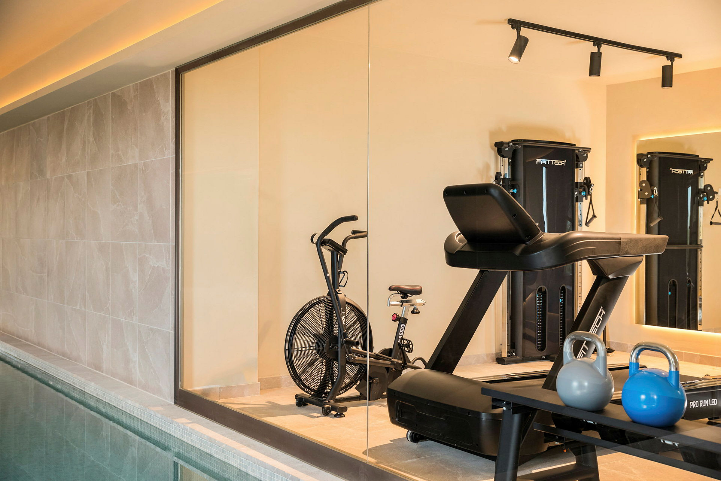 Ett gym med träningsmaskiner, kettlebells och en motionscykel i förgrunden. (AI-genererad text)