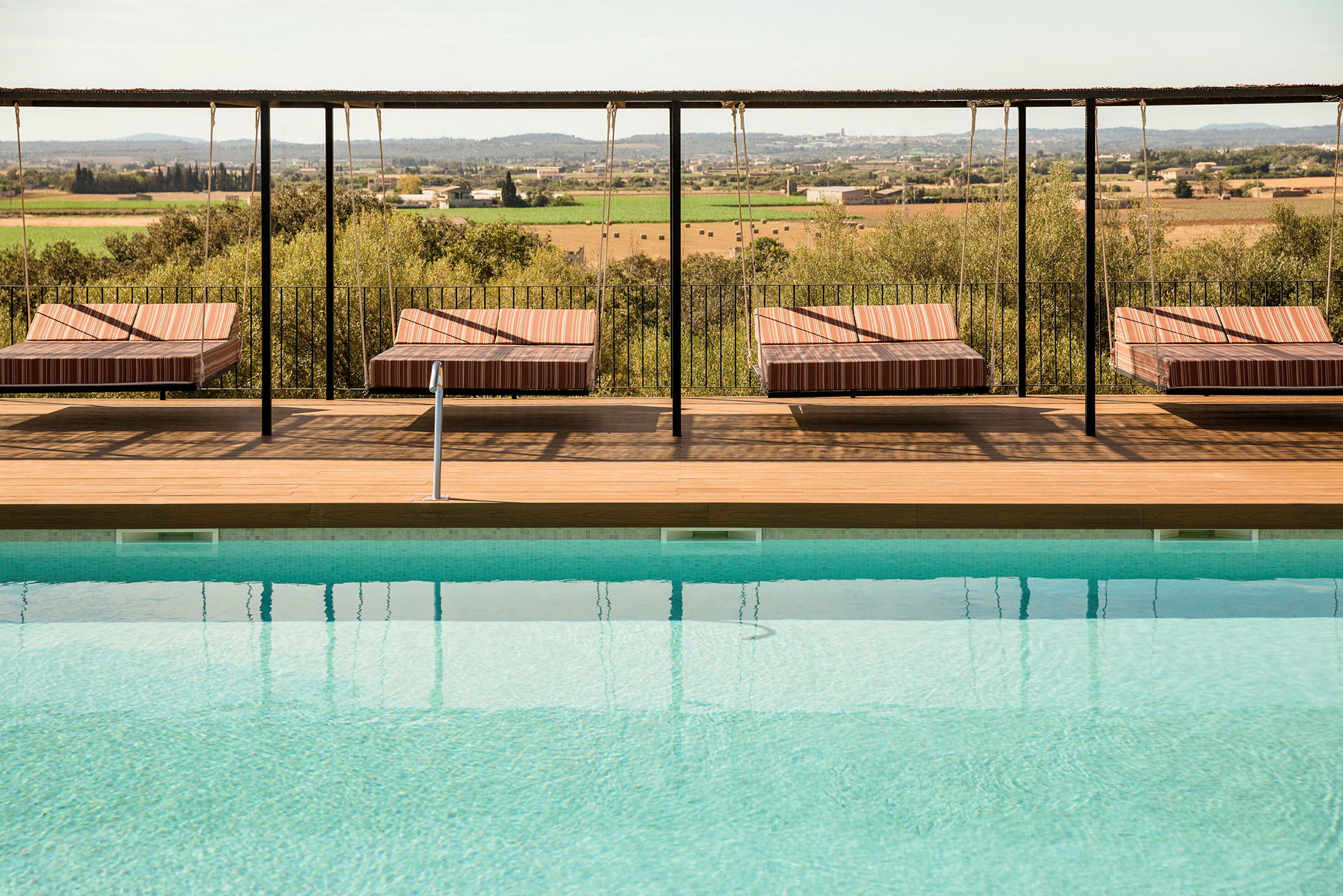 Pool med vilstolar och utsikt över landskap. (AI-genererad text)